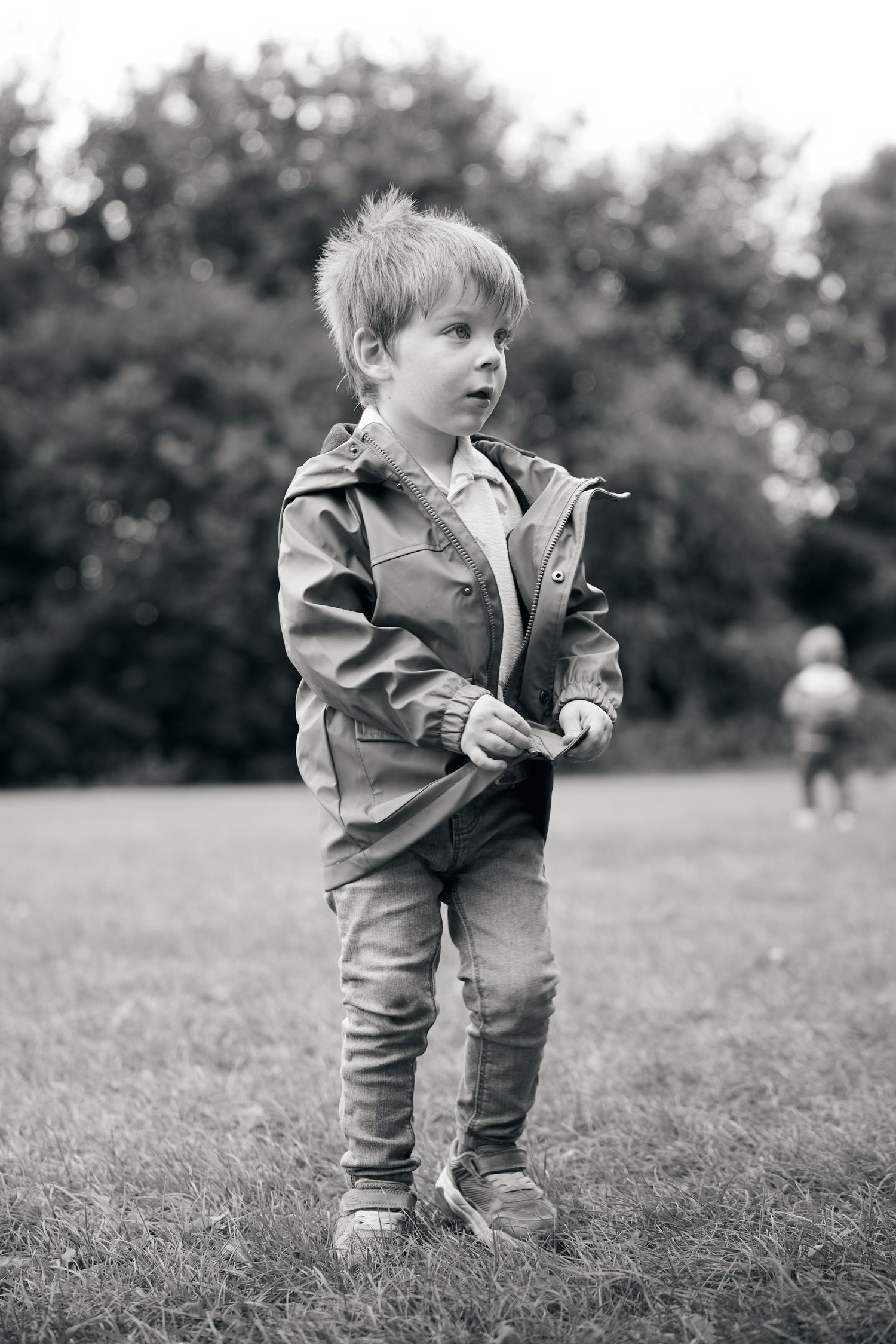 Black and white photo of toddler playing in grass field.