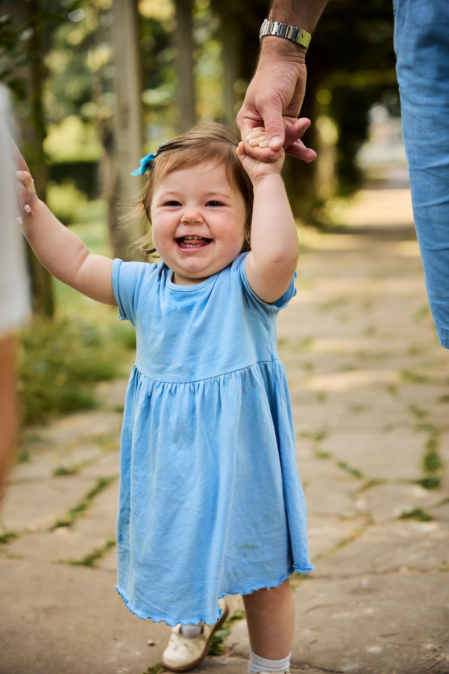 Sequence showing happy child in blue dress being lifted up while laughing.