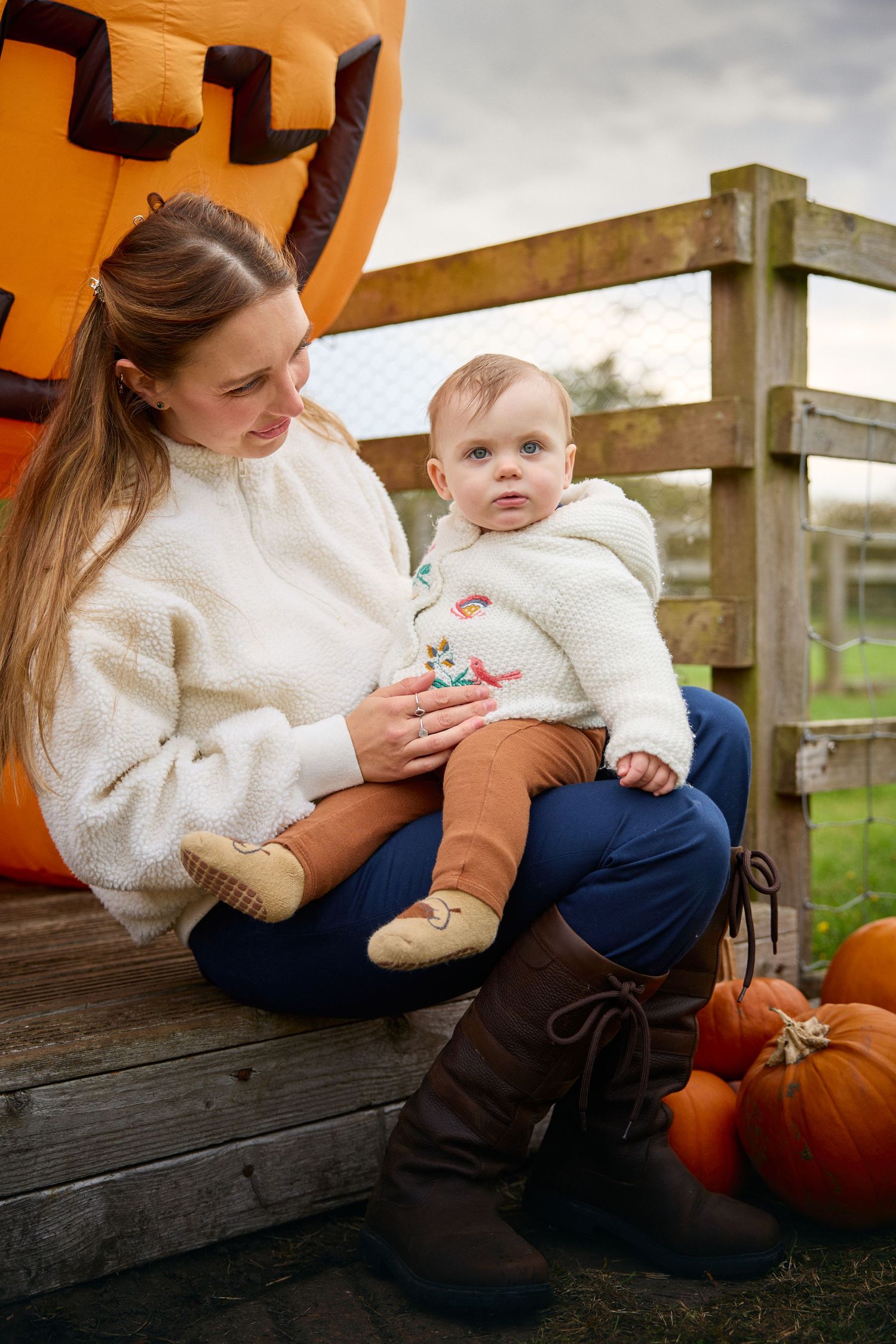 Family sitting on wooden bench with pumpkins during fall photoshoot.