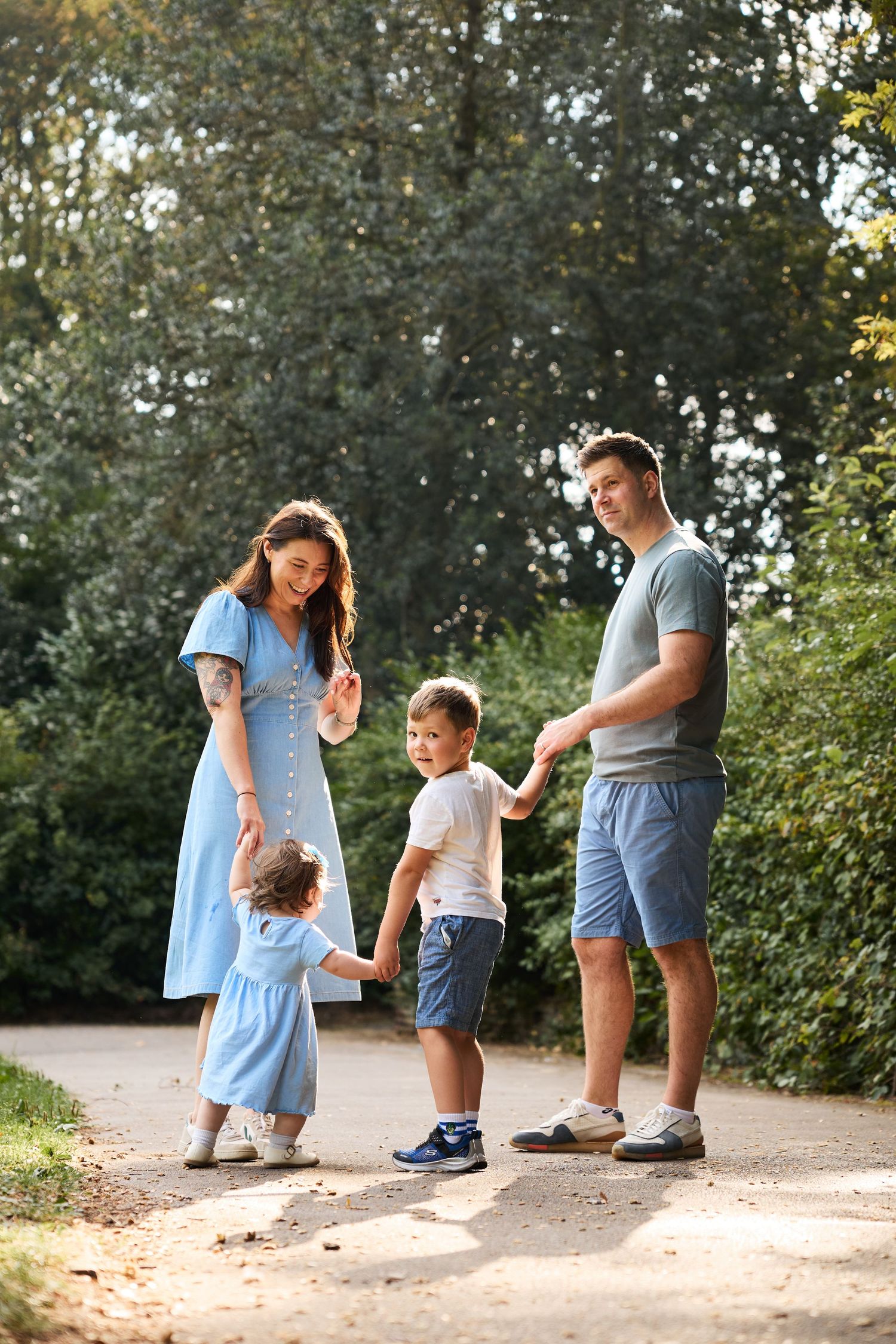 Family members interact playfully on a dirt path surrounded by green foliage.