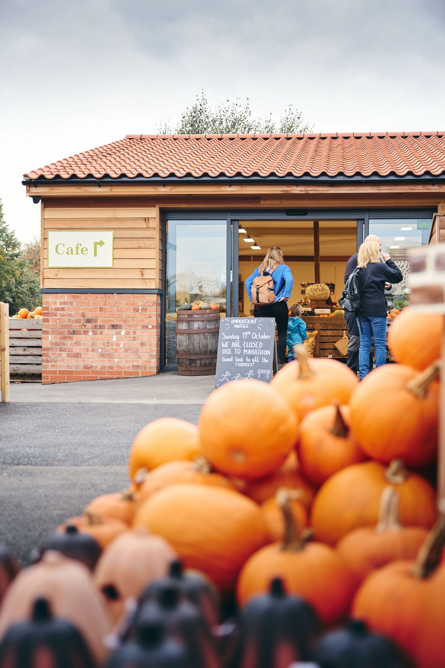 Rustic farm stand with terracotta roof and wooden exterior displaying seasonal pumpkins.