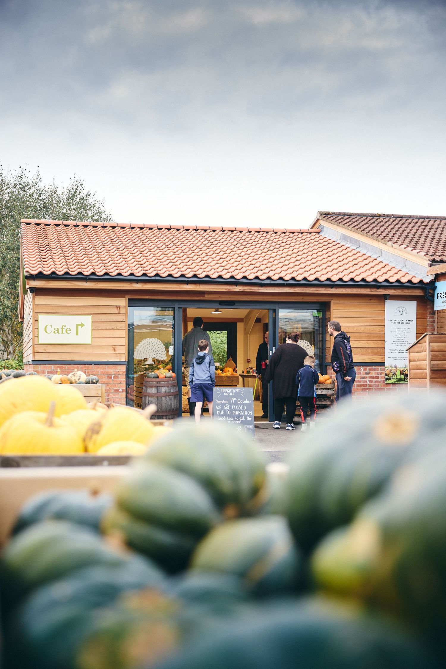 Farm shop building with terra cotta roof tiles and wooden siding at a pumpkin patch.