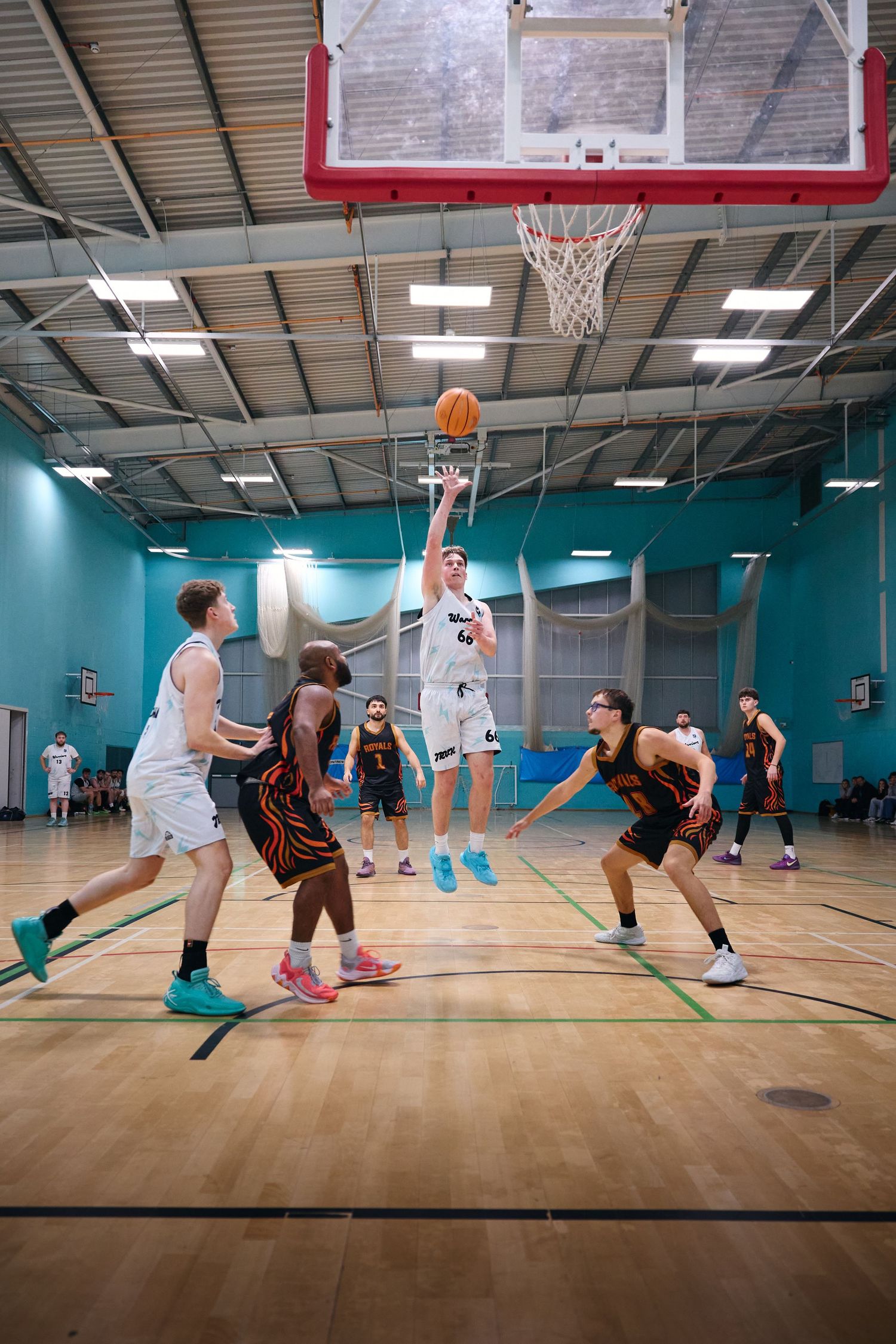 Wide view of basketball game showing players spread across indoor court.