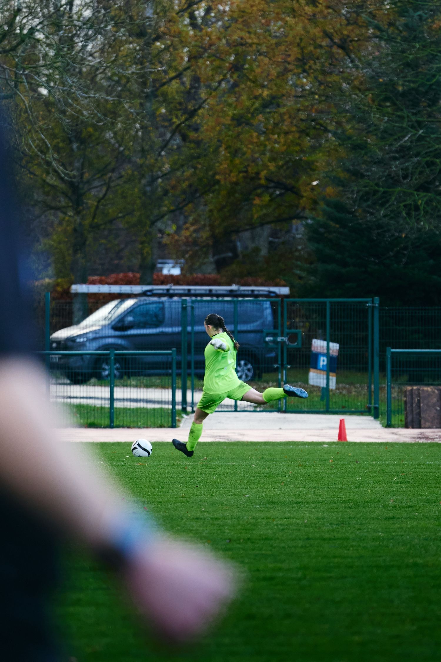 Soccer goalkeeper in bright yellow uniform making a kick on artificial turf field during a match.