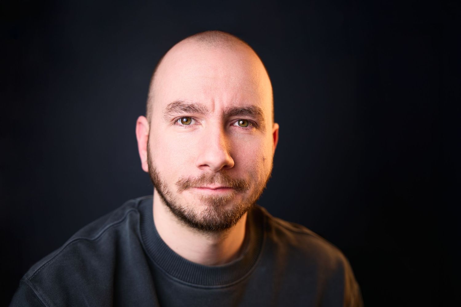 Professional headshot series against black background showing different expressions.