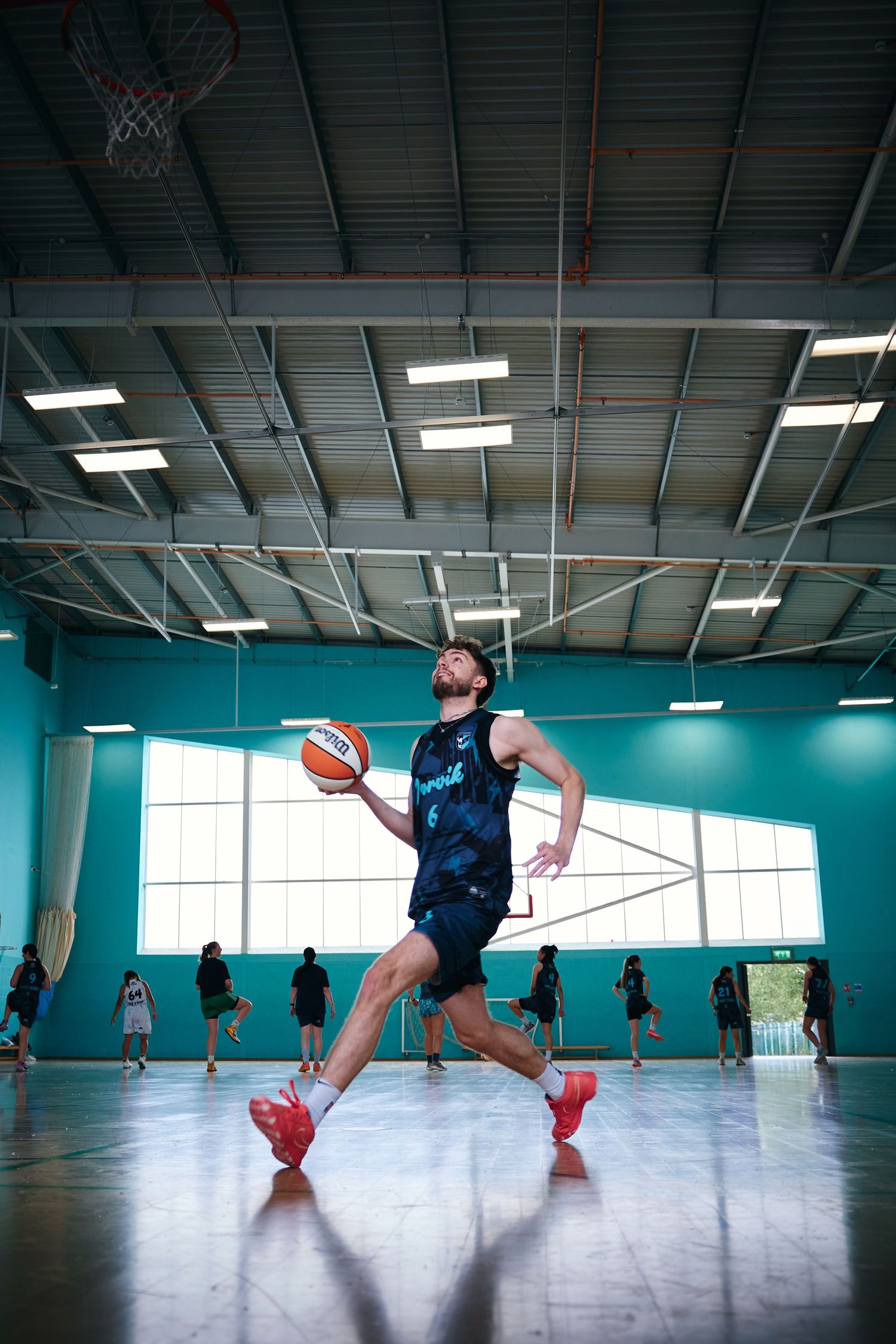 Dynamic sequence of basketball player running and jumping in indoor sports facility.