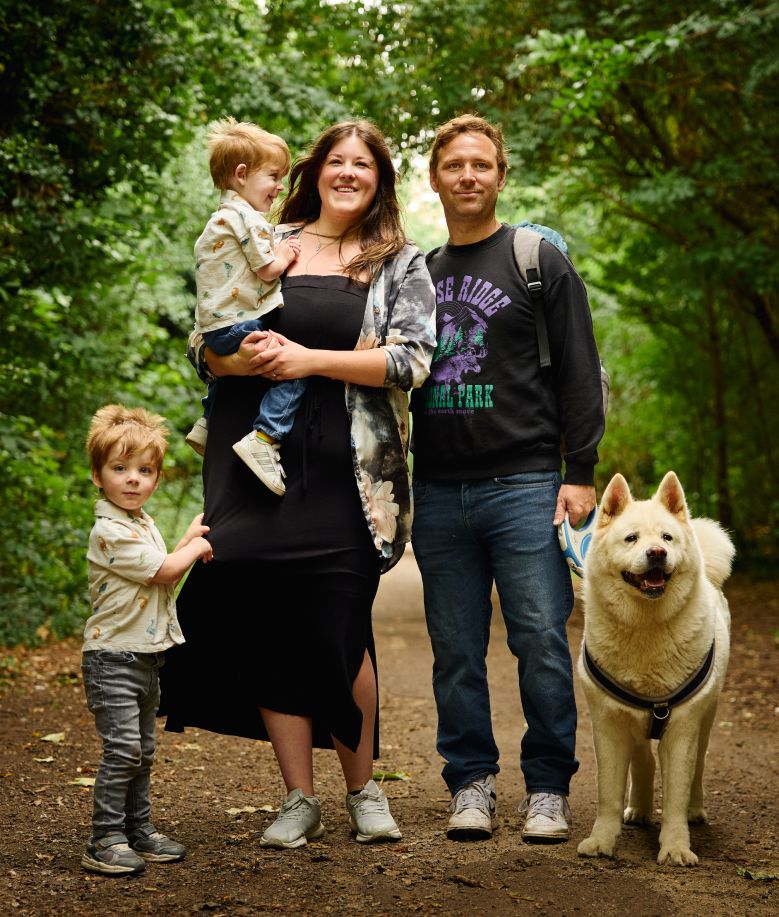 A family walking on a forest trail with their fluffy Akita dog on a nature adventure.