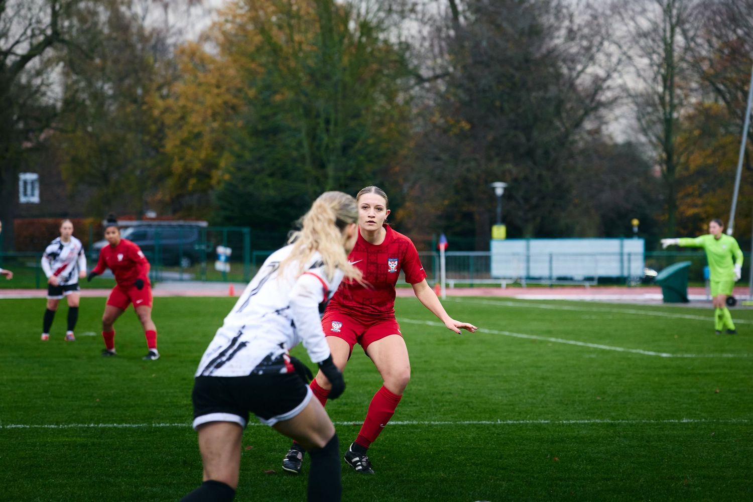 Soccer players compete for possession of the ball during an intense match on a grass field in autumn weather.