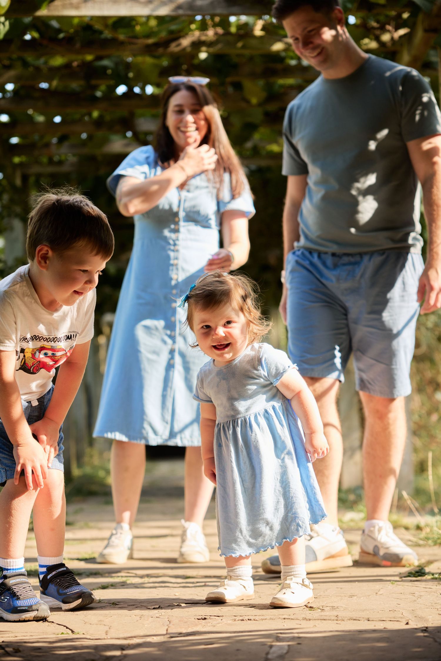 Playful family moment captured from ground level on stone garden path.