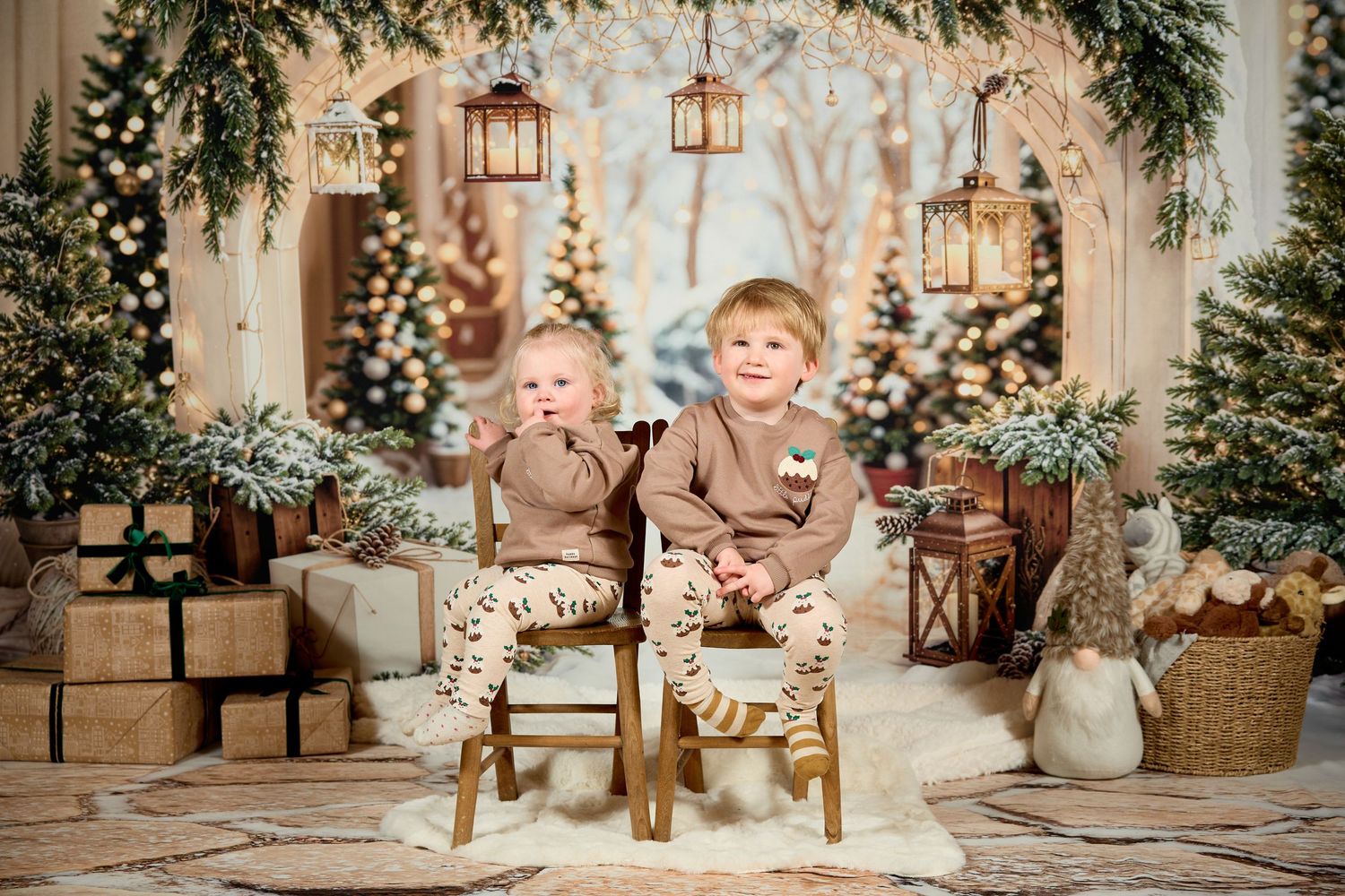 Festive winter holiday photo session setup with rustic decor, evergreen garlands, and warm glowing lanterns.
