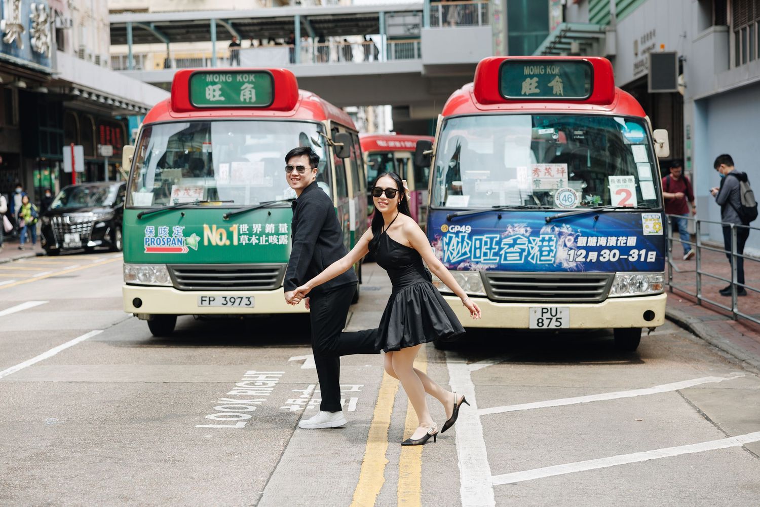 Hong Kong green and red taxi cabs line up at a taxi stand on a city street with pedestrians walking by. Couple Photoshoot in Mong Kok, HK