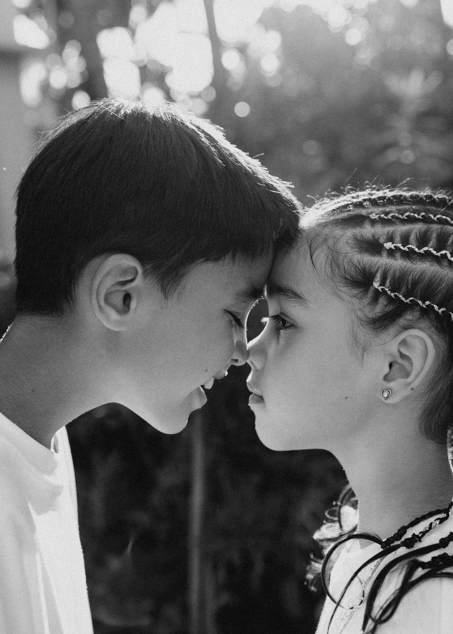Sweet black and white portrait of two young children touching noses together, with one wearing braided hair. hong kong family photographer