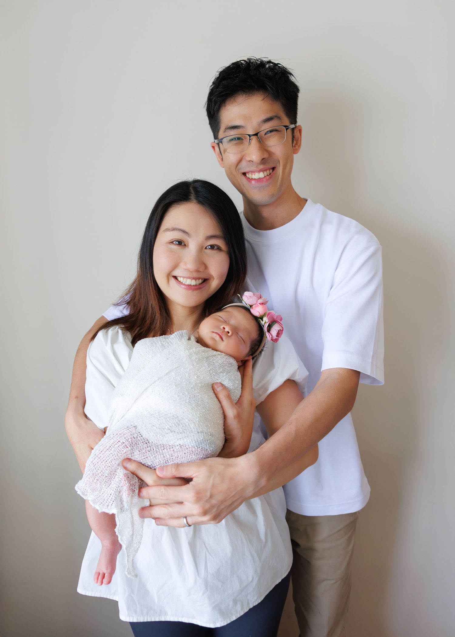 Four progressive photos show a couple hugging and sharing joyful moments against a neutral wall background. Newborn Photoshoot in Hong Kong