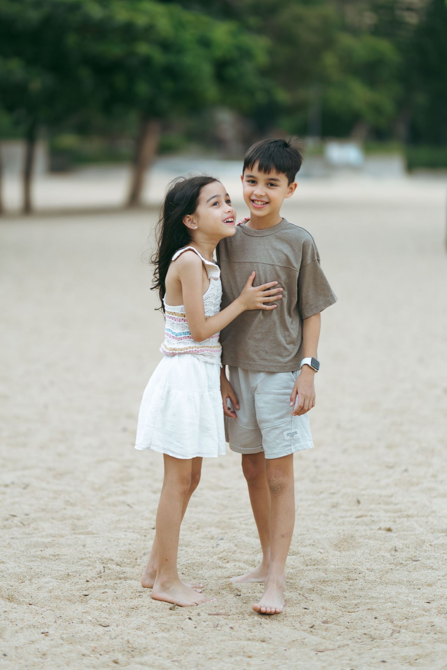 Two children share joyful moments together while playing on sandy beach. Family Photoshoot in Hong Kong