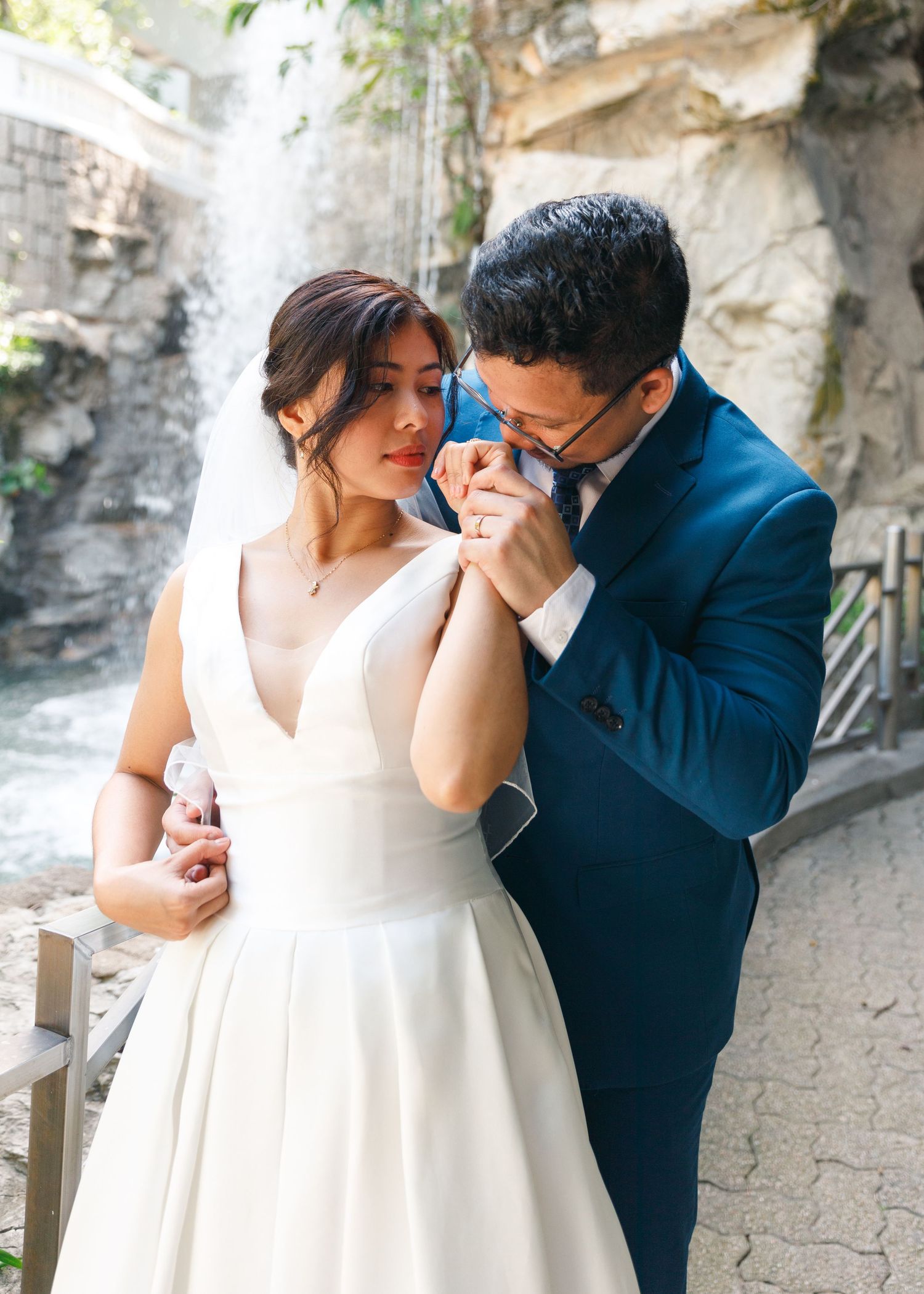 A romantic wedding couple share an intimate moment outdoors in front of a stone wall. Civil Ceremony in Hong Kong