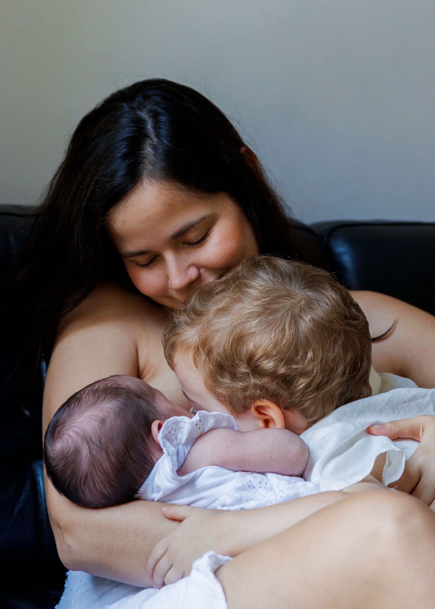 Baby being held against parent's chest while sleeping peacefully in white clothing. Newborn Photographer in Hong Kong