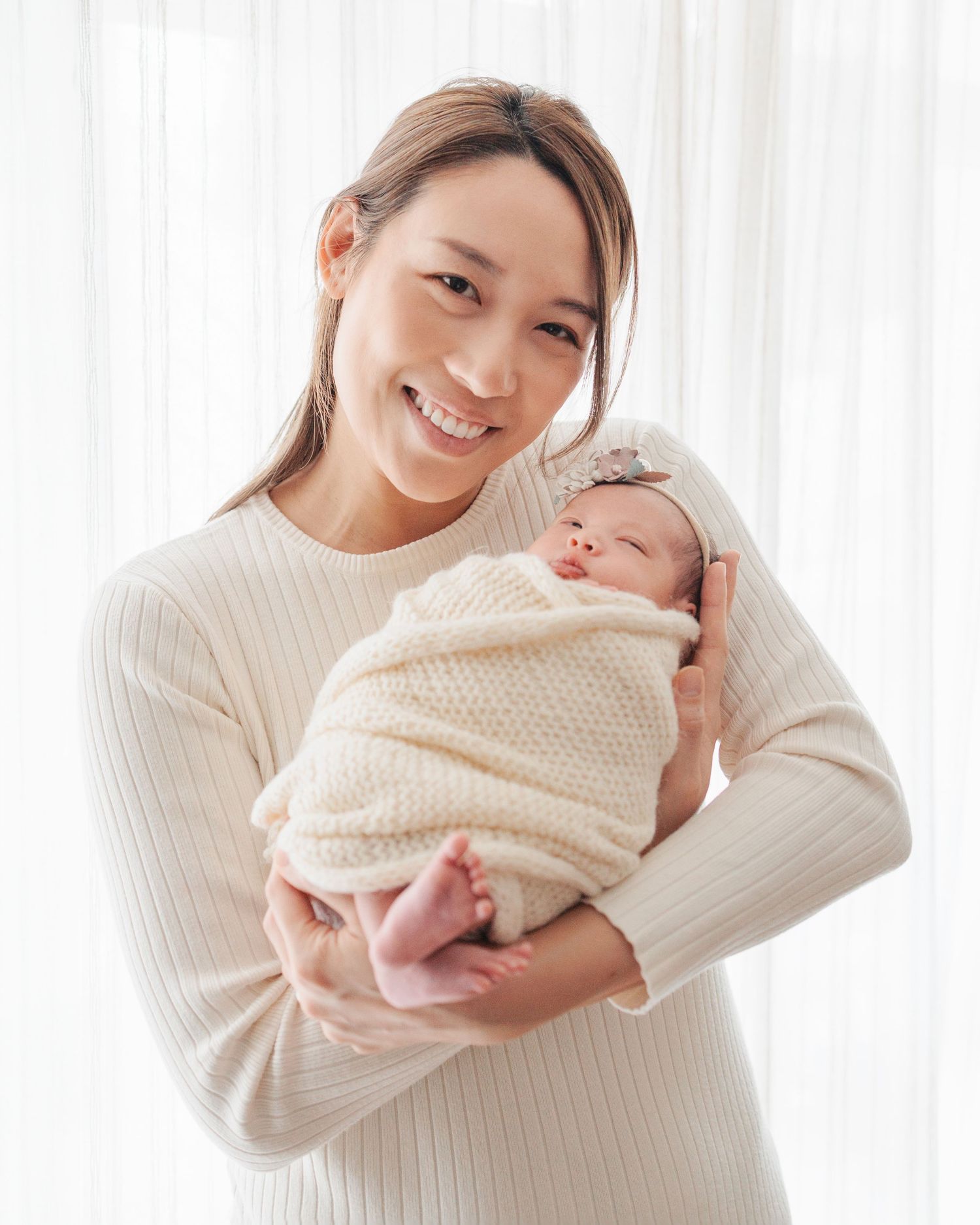 Four connected photos showing someone wearing a cream sweater holding and cuddling a small baby in peaceful poses. In-home newborn session