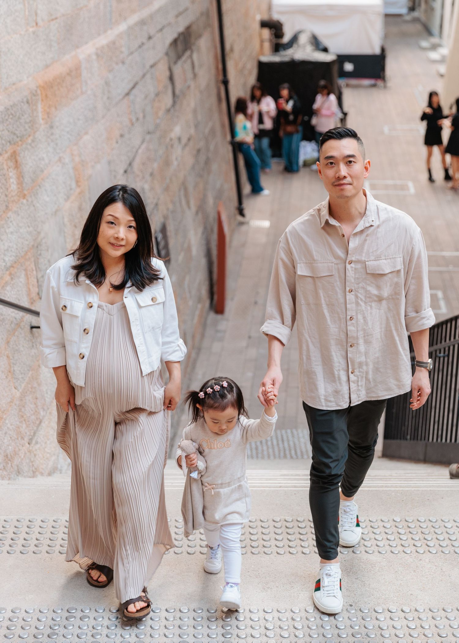 A couple in light colored outfits walking up concrete stairs together, shown in multiple candid moments. Family Photoshoot in Hong Kong