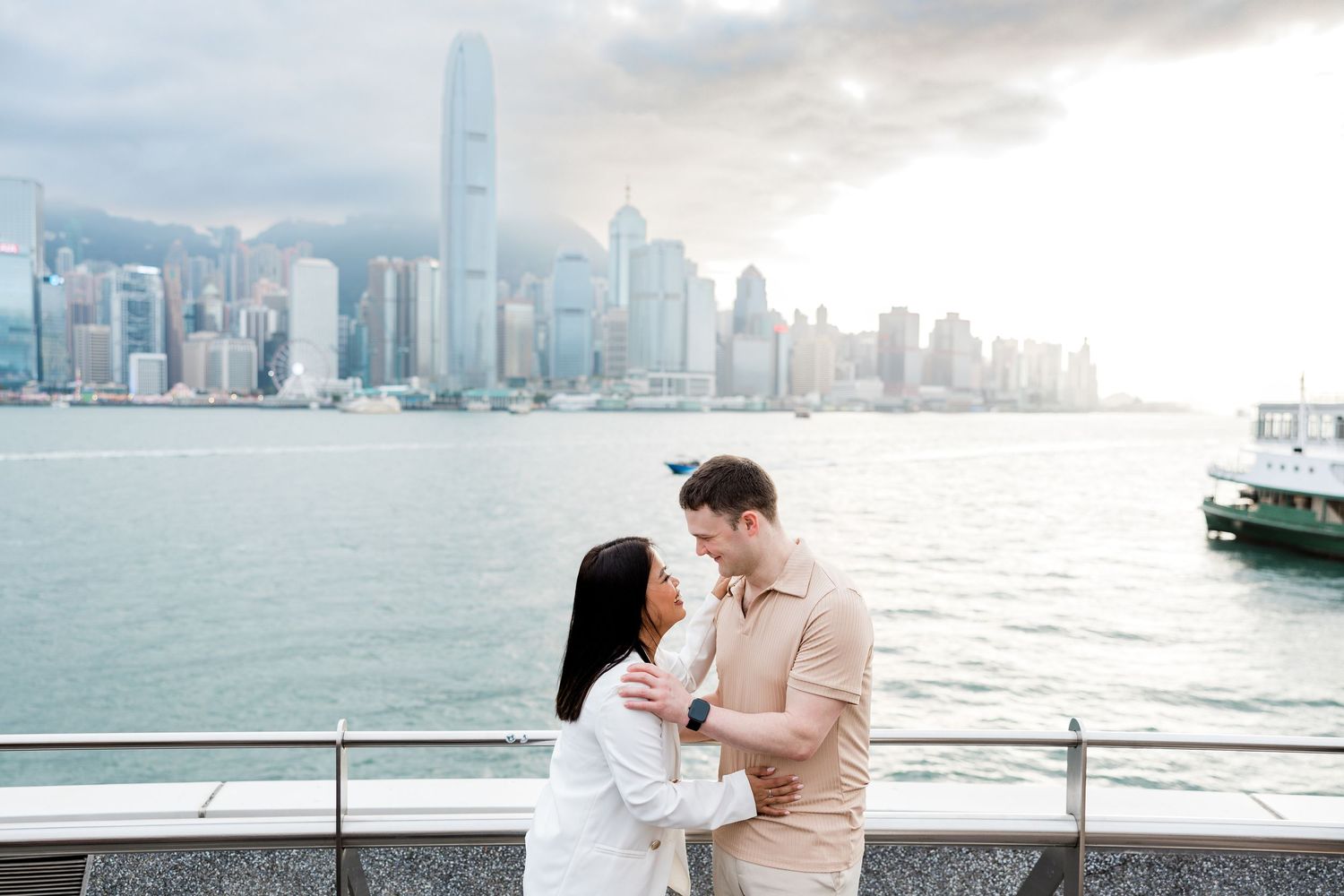 Couple sharing tender moments against Hong Kong's iconic waterfront skyline on a cloudy afternoon. Couple Session in Hong Kong
