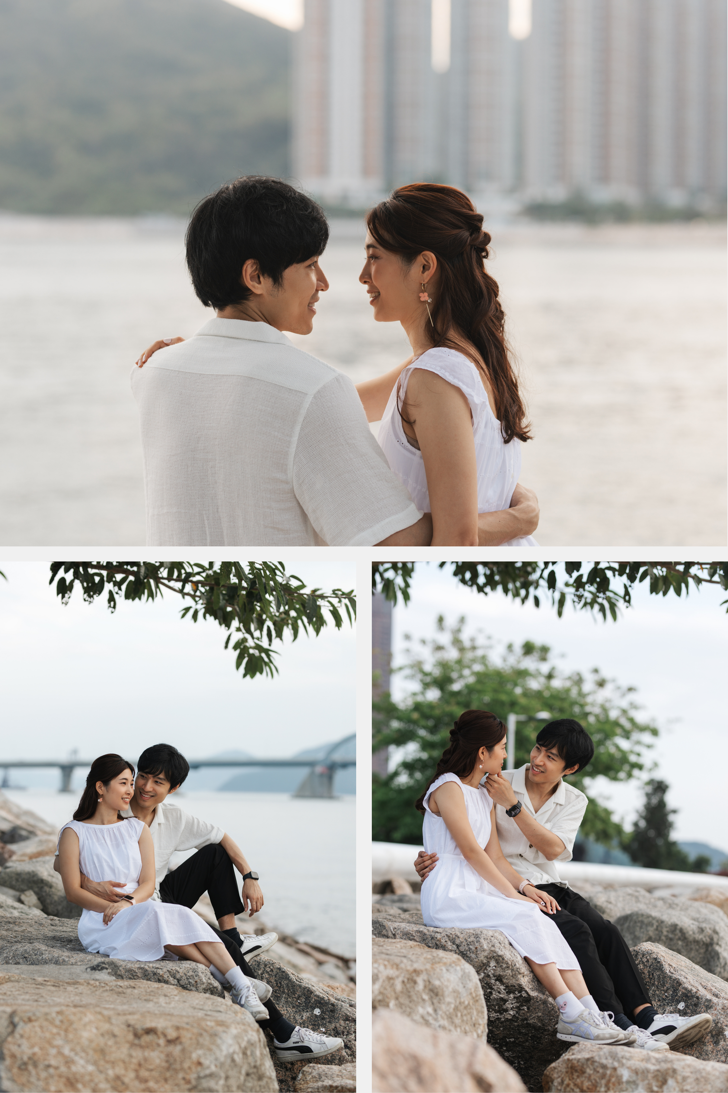 Romantic couple in white outfits sharing intimate moments on rocky waterfront with urban backdrop. Couple Photoshoot in Hong Kong