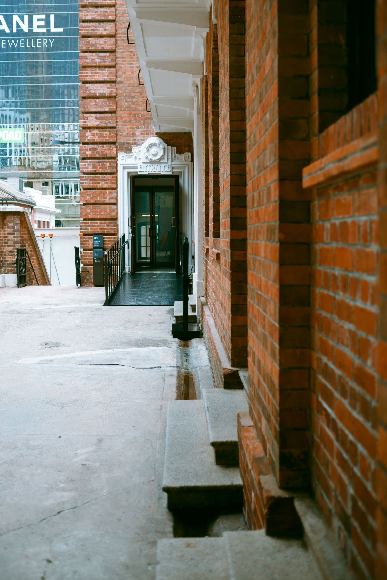 Brick-lined retail corridor with exposed columns and white floor. Taikwun, Hong Kong