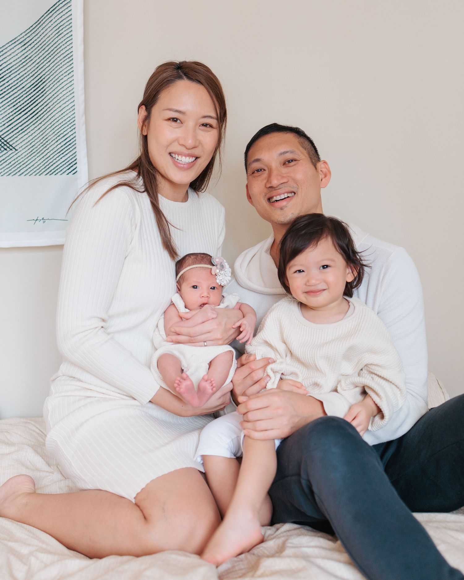 A family wearing matching white outfits sits together on a gray couch in a series of casual lifestyle photos. In-home newborn session in HK