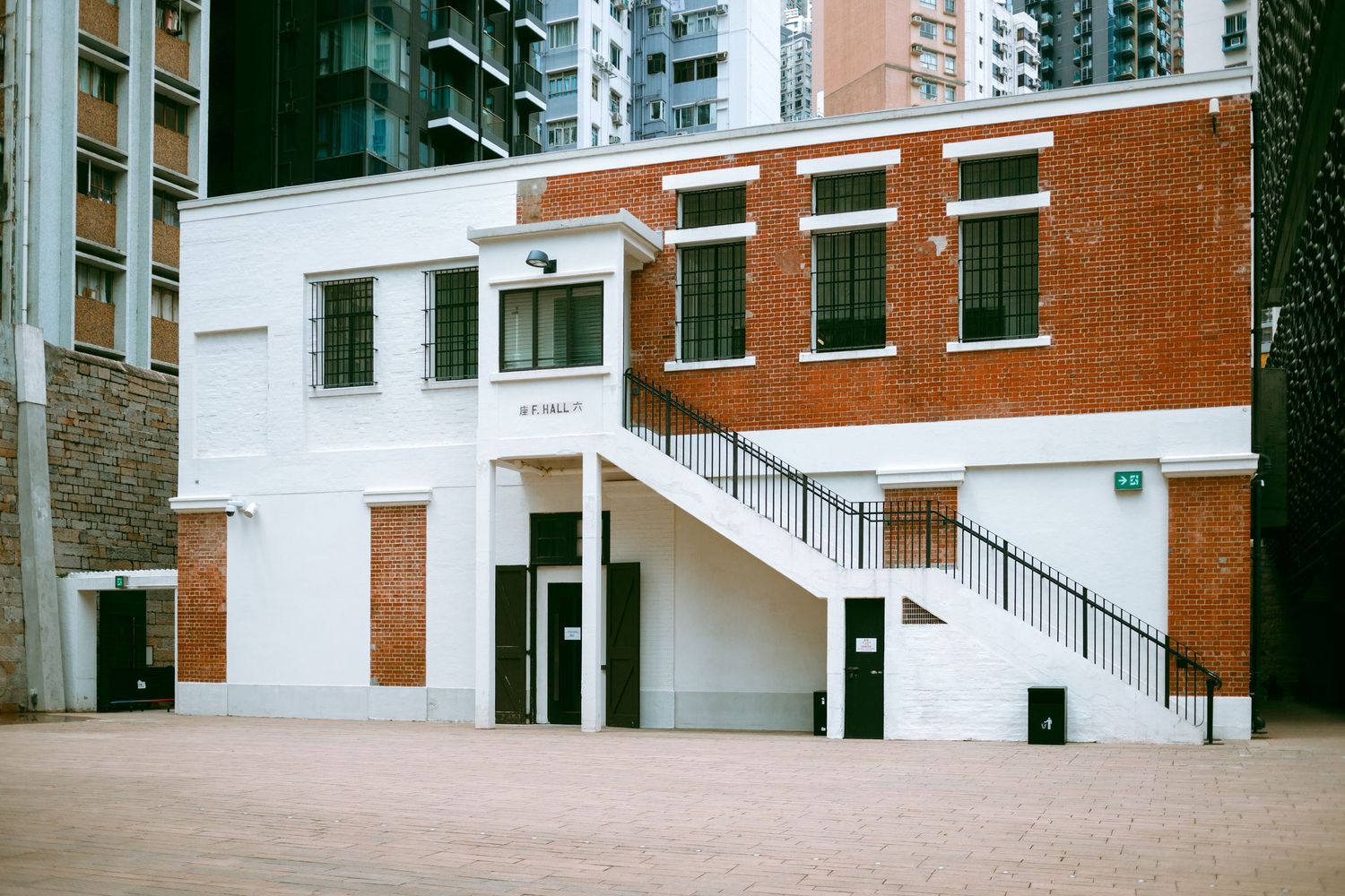 Modern brick apartment building with white stairs and entryway details against an urban backdrop of high-rise buildings. Taikwun, Hong Kong