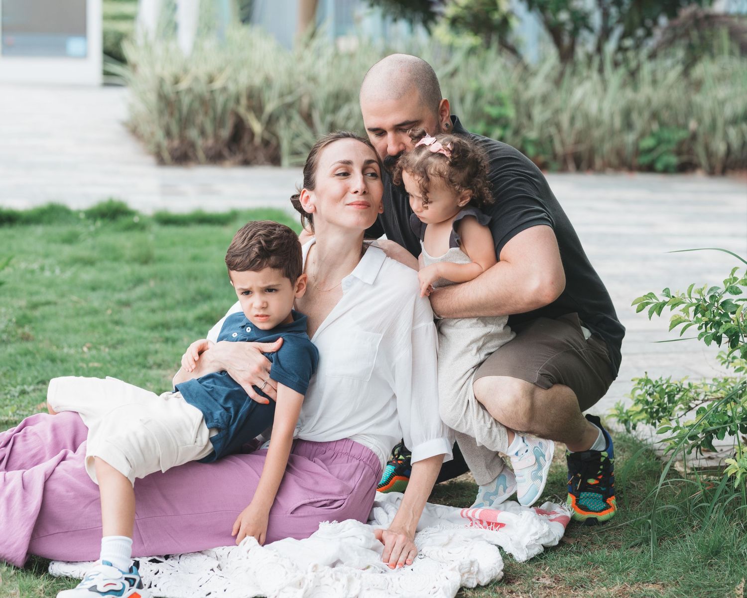 A series of intimate candid moments shows people laying on a blanket together in a grassy outdoor setting. Family Photoshoot in Hong Kong