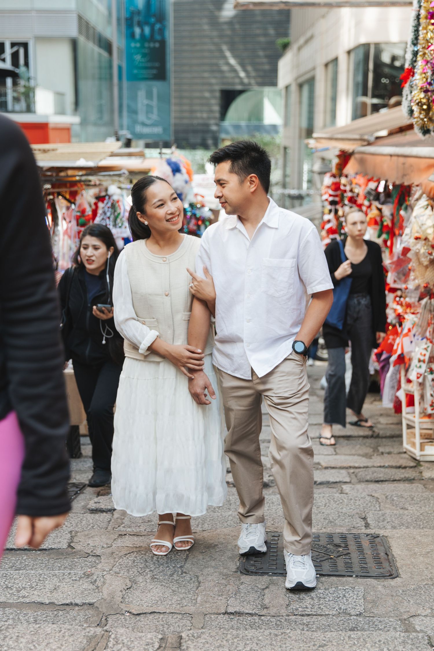 Happy couplelaughing and walking down an urban street decorated with festive red ornaments. Couple Photoshoot in Central, Hong Kong