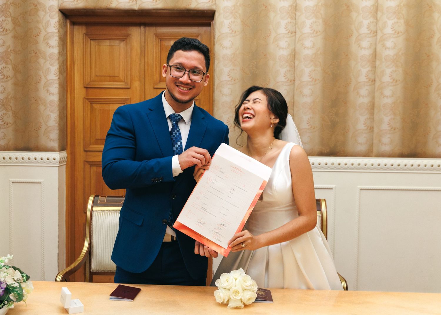 Couple shares joyful laughter while going through paperwork at a formal signing ceremony. Civil Ceremony in Hong Kong