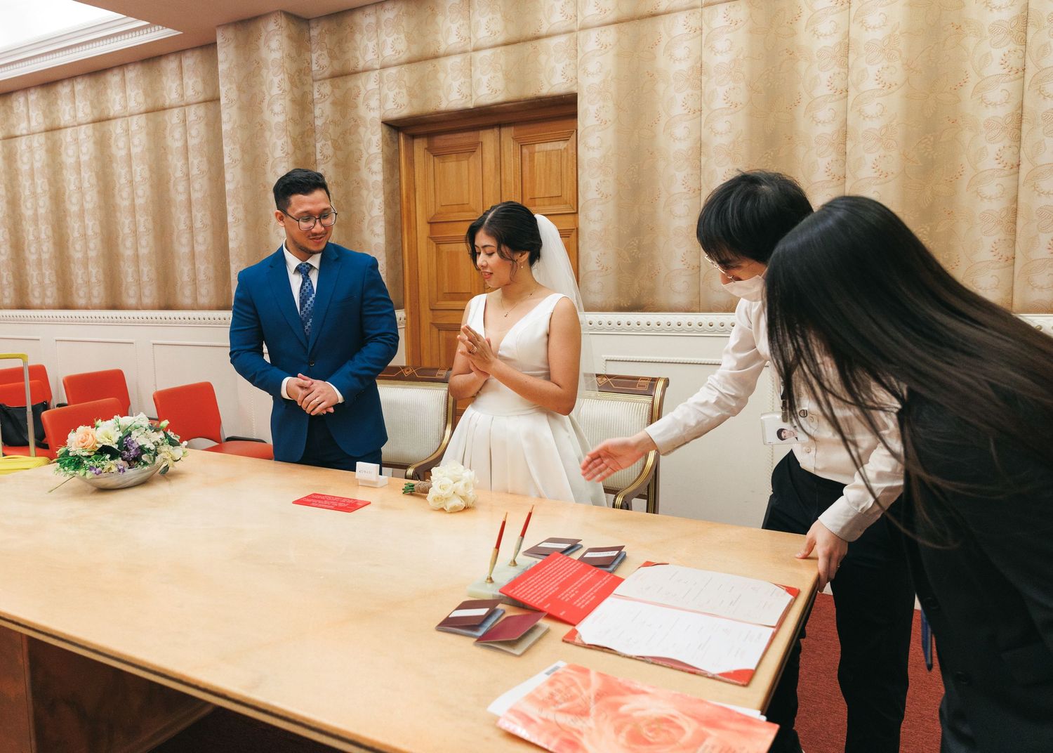 couple documents at a table during a formal ceremony in a bright room with tan curtains in the background. Civil Ceremony in Hong Kong