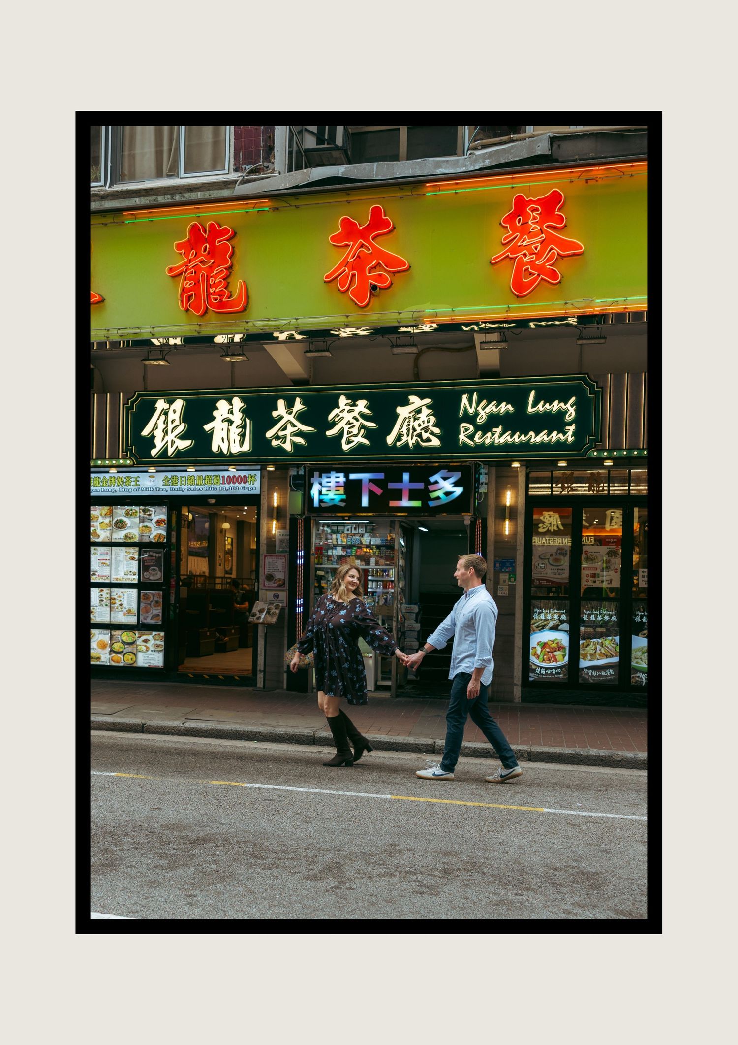 Couple holding hands walking past Ngan Lung Restaurant with bright Chinese neon signs in Hong Kong. couple session in Hong Kong. Pre Wedding