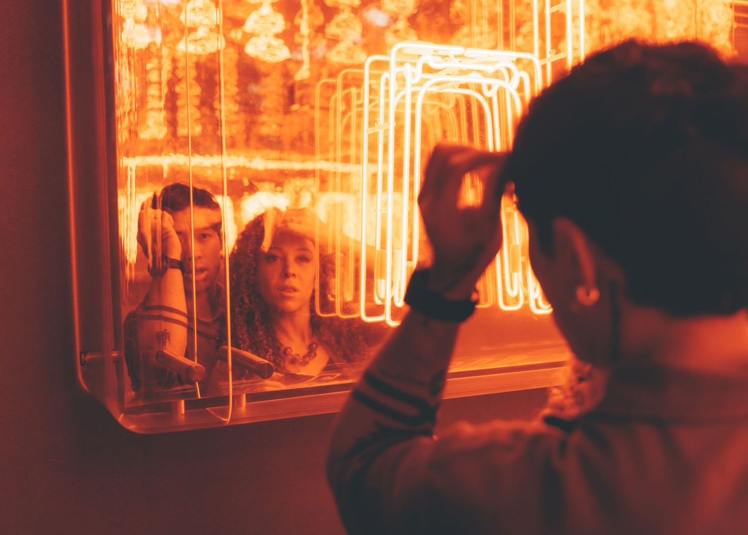 couple stands silhouetted against a red-orange neon-lit backdrop creating a moody Couple Photoshoot in Hong Kong