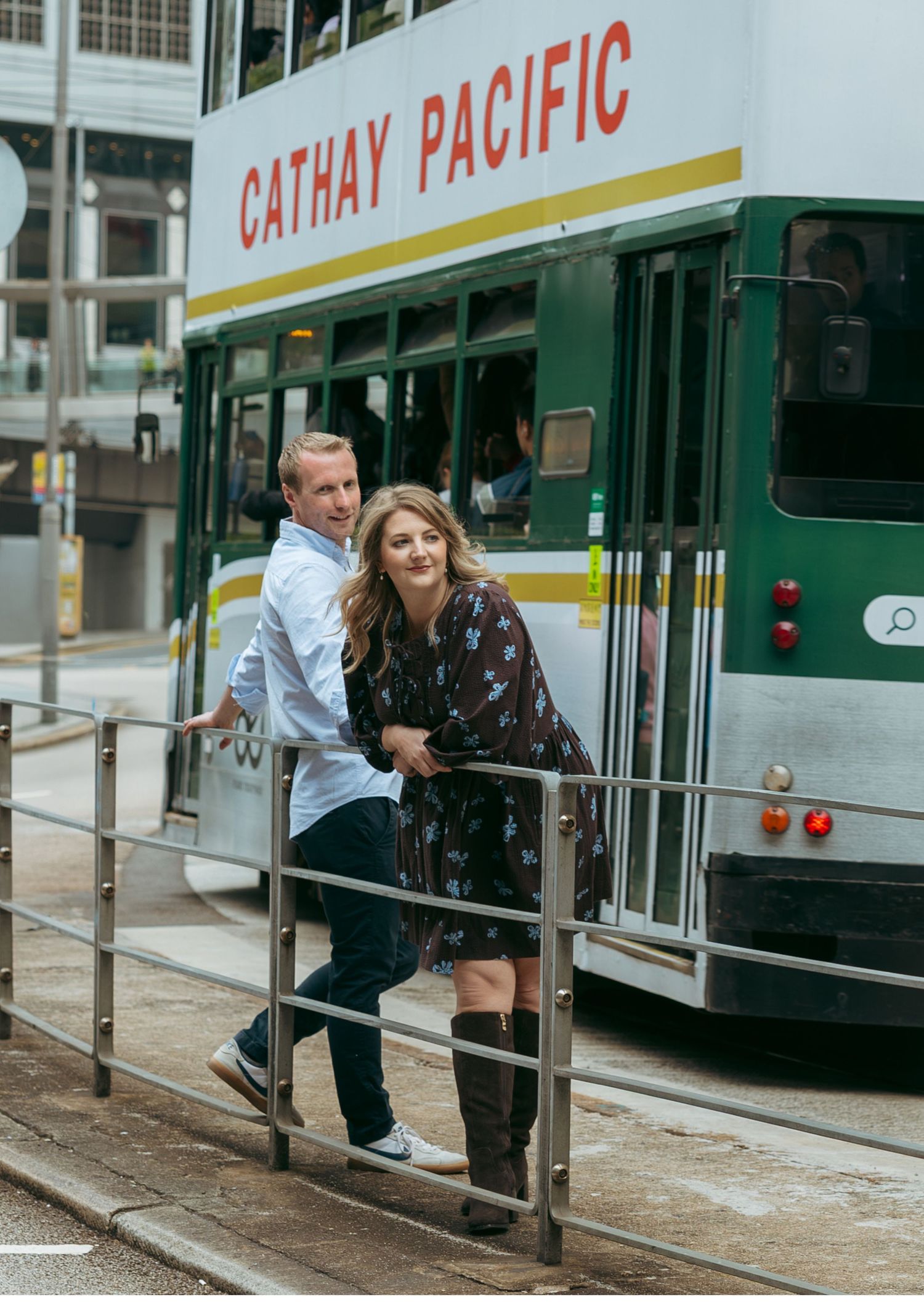 Couple posing in front of a Cathay Pacific tram on a wet street in Hong Kong. couple session in Hong Kong. Pre Wedding HK