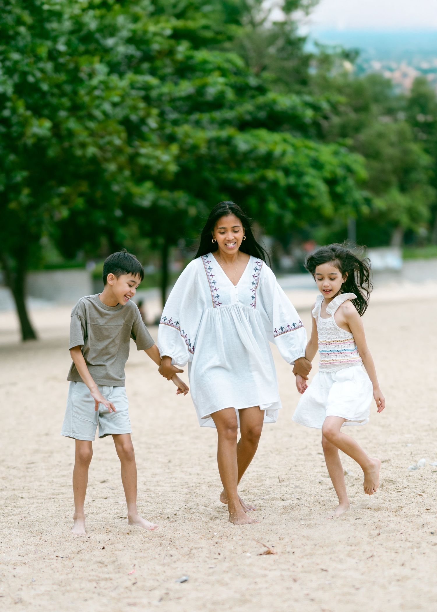 People in casual wear playfully exercising or doing a leg movement sequence together on a sandy beach. Chatty Losty Photography