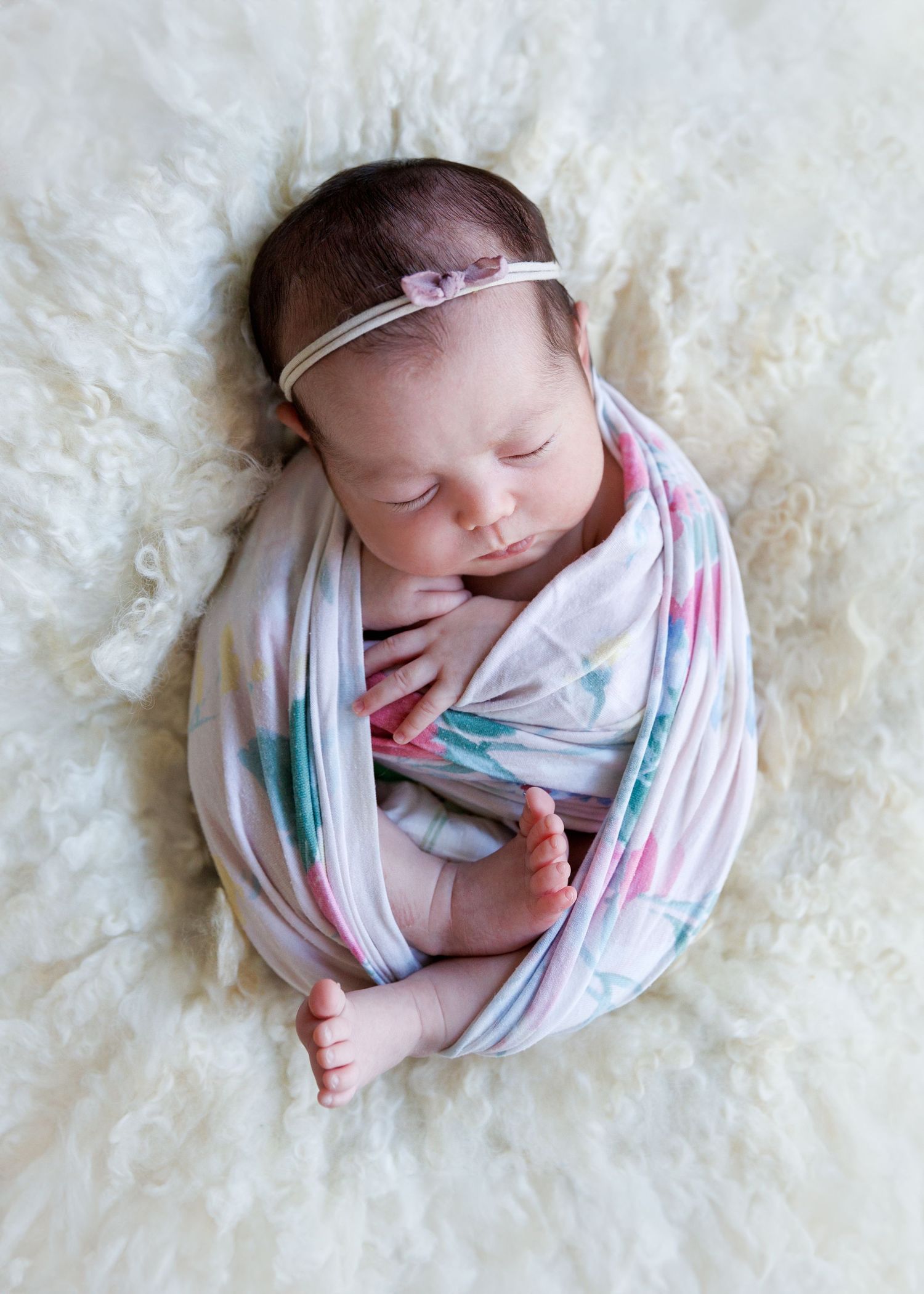 Sleeping newborn swaddled in striped blanket lies on soft white textured background in four similar poses. Newborn Photographer in Hong Kong