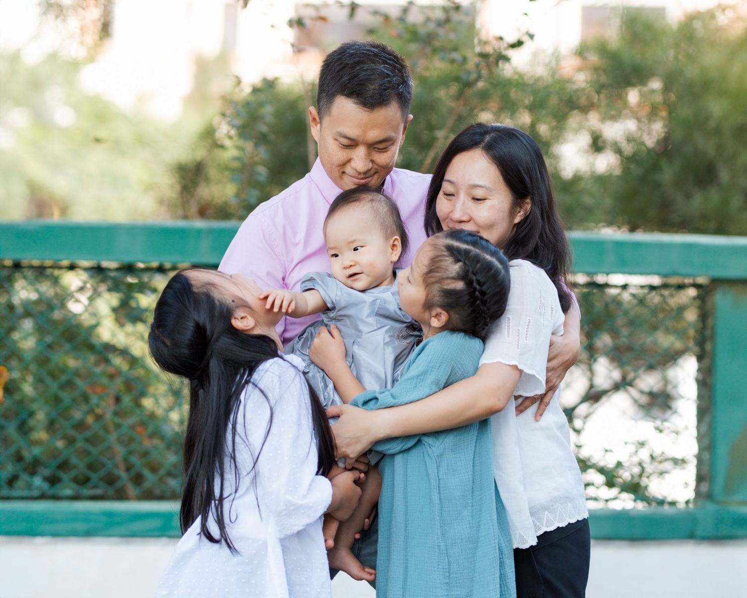 Family wearing coordinated blue and white outfits share tender moments in outdoor portrait session. Hong Kong Family Photographer