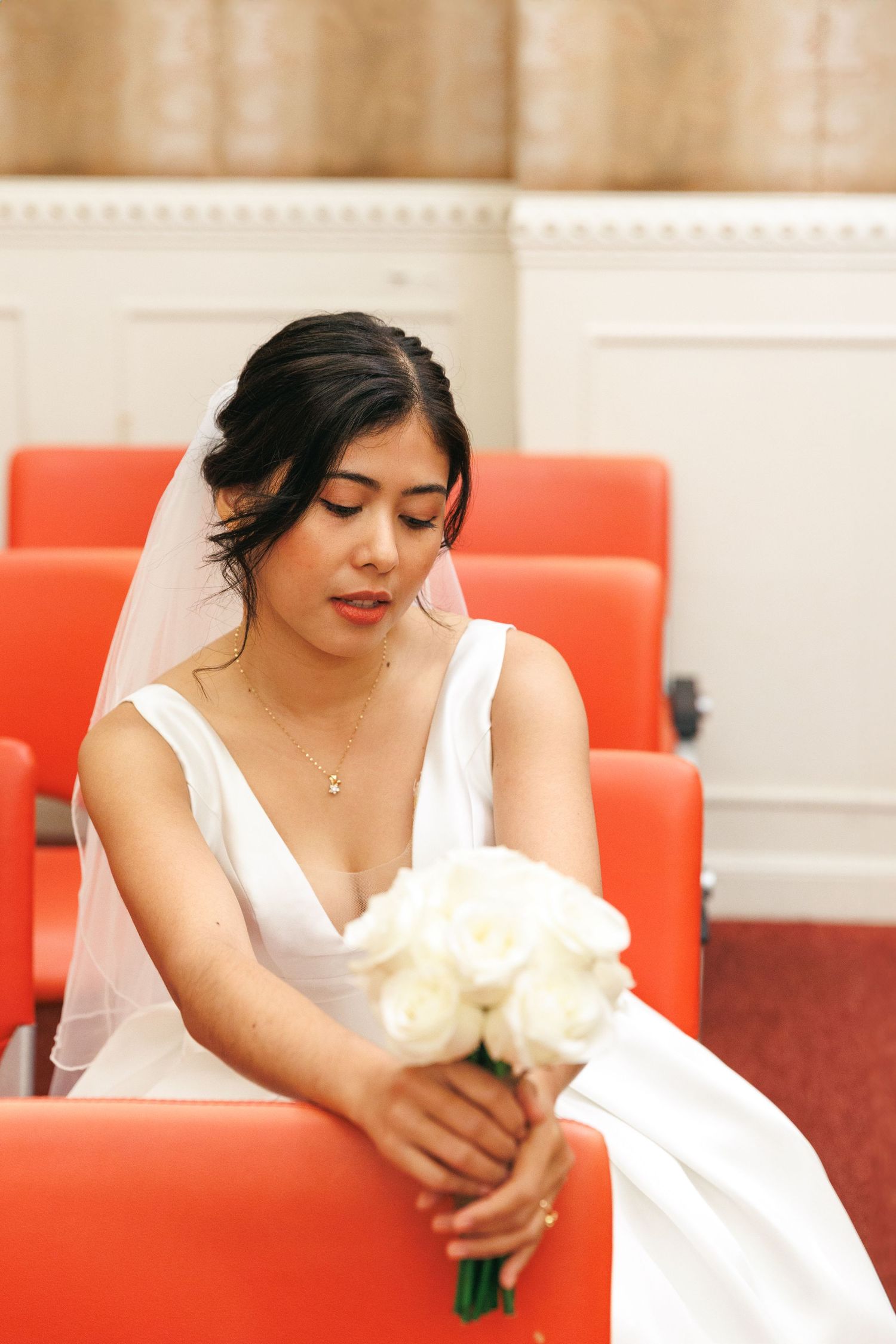 A bride in a white wedding gown poses gracefully on white flowers. Civil Ceremony in Hong Kong
