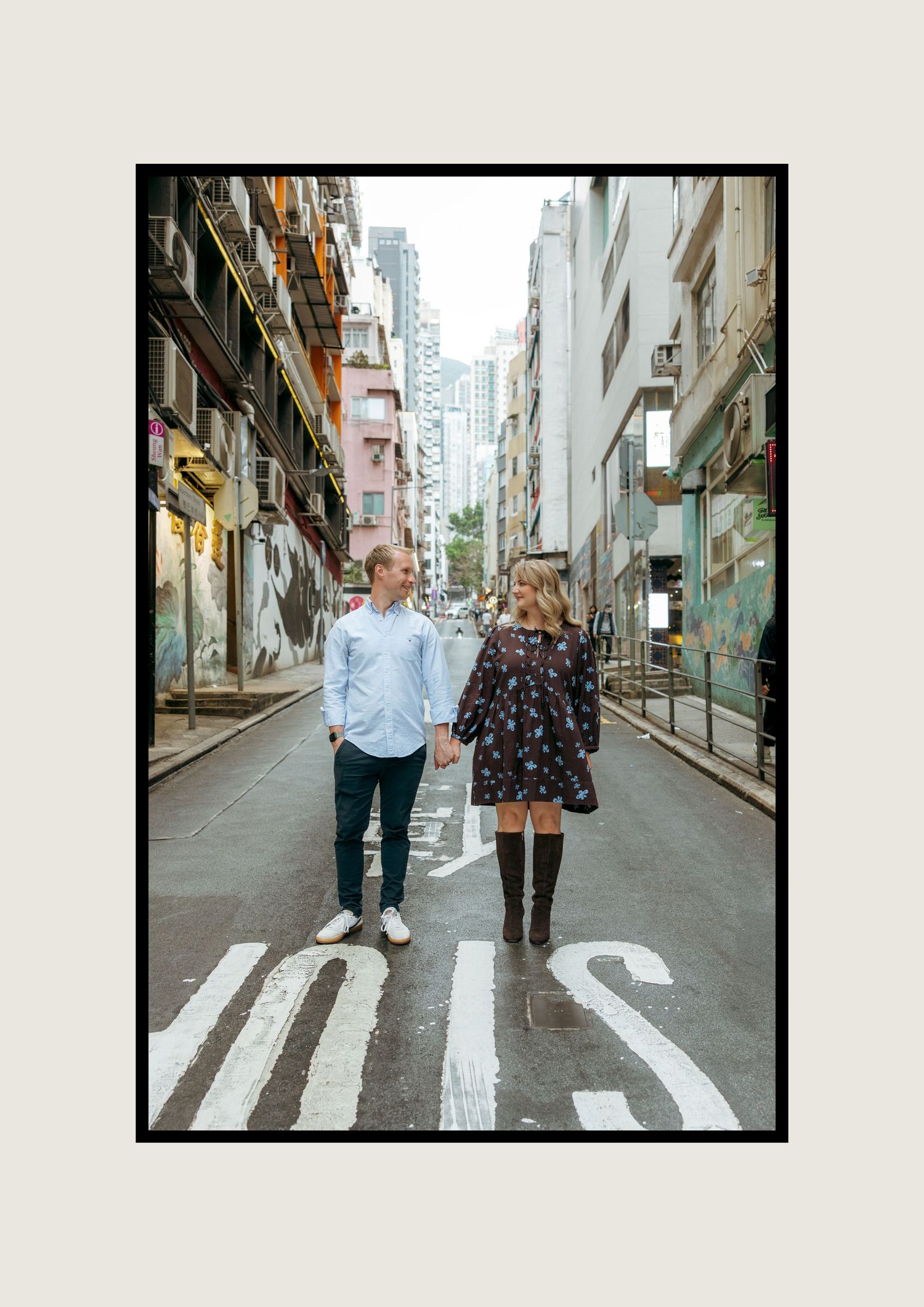 Couple holding hands walking down an urban alley street, posing for an engagement photo in a city. couple session in Hong Kong. Pre Wedding