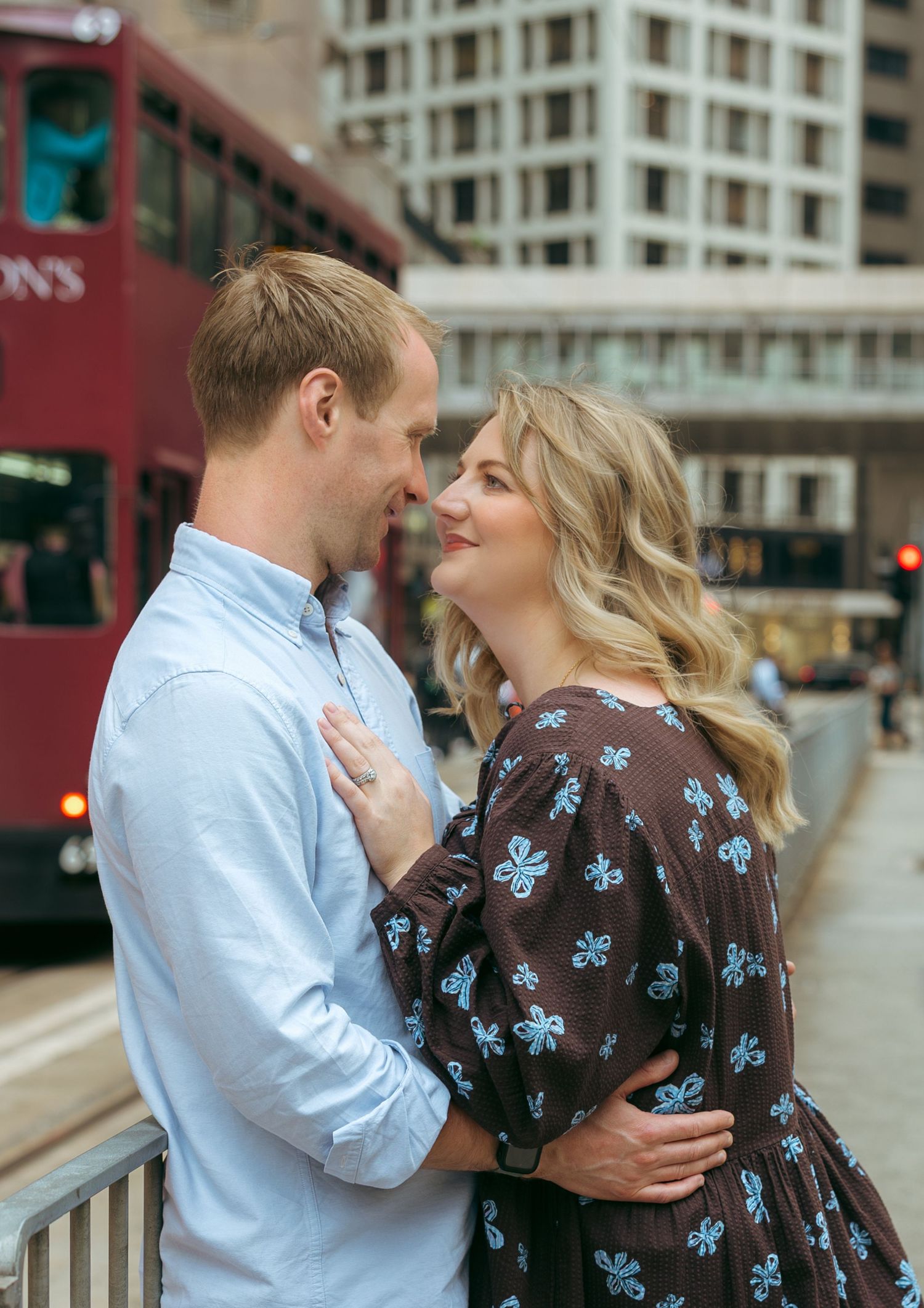 Couple sharing a romantic moment on a city street with a red double-decker bus in the background. couple session in Hong Kong. Pre Wedding