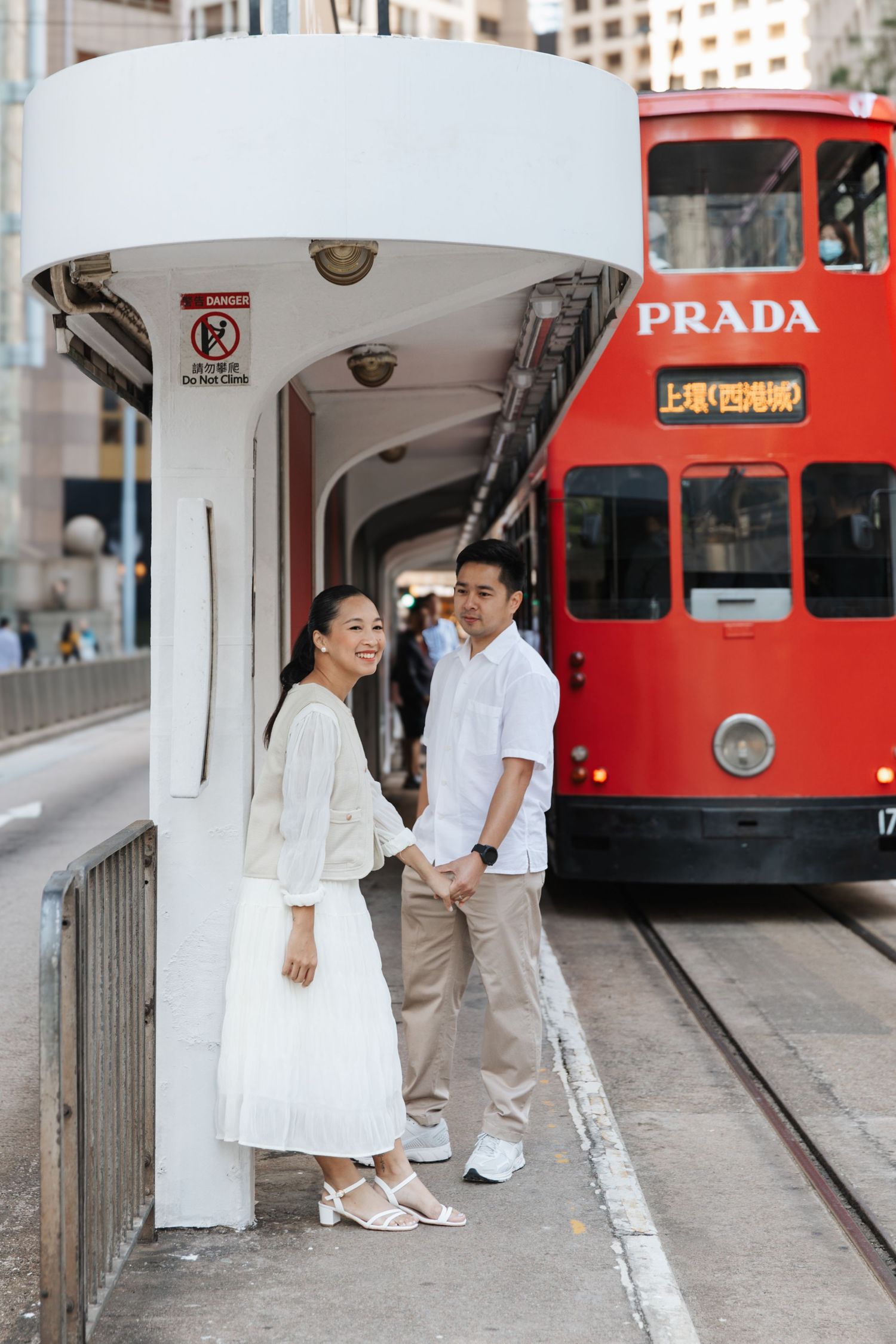 A romantic moment captured by a red tram in Hong Kong with couple dressed in white outfits and warm lighting. Couple Photoshoot in Central