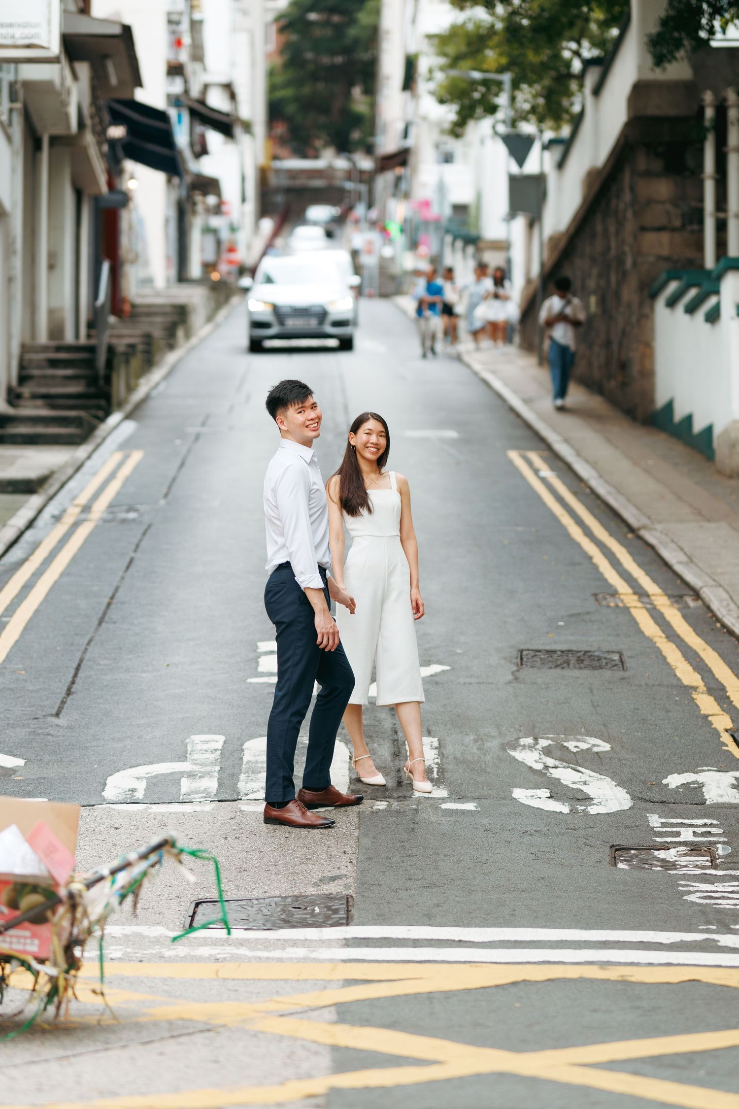 A couple in urban street with double yellow lines and buildings in the background. Couple Photoshoot in Hong Kong