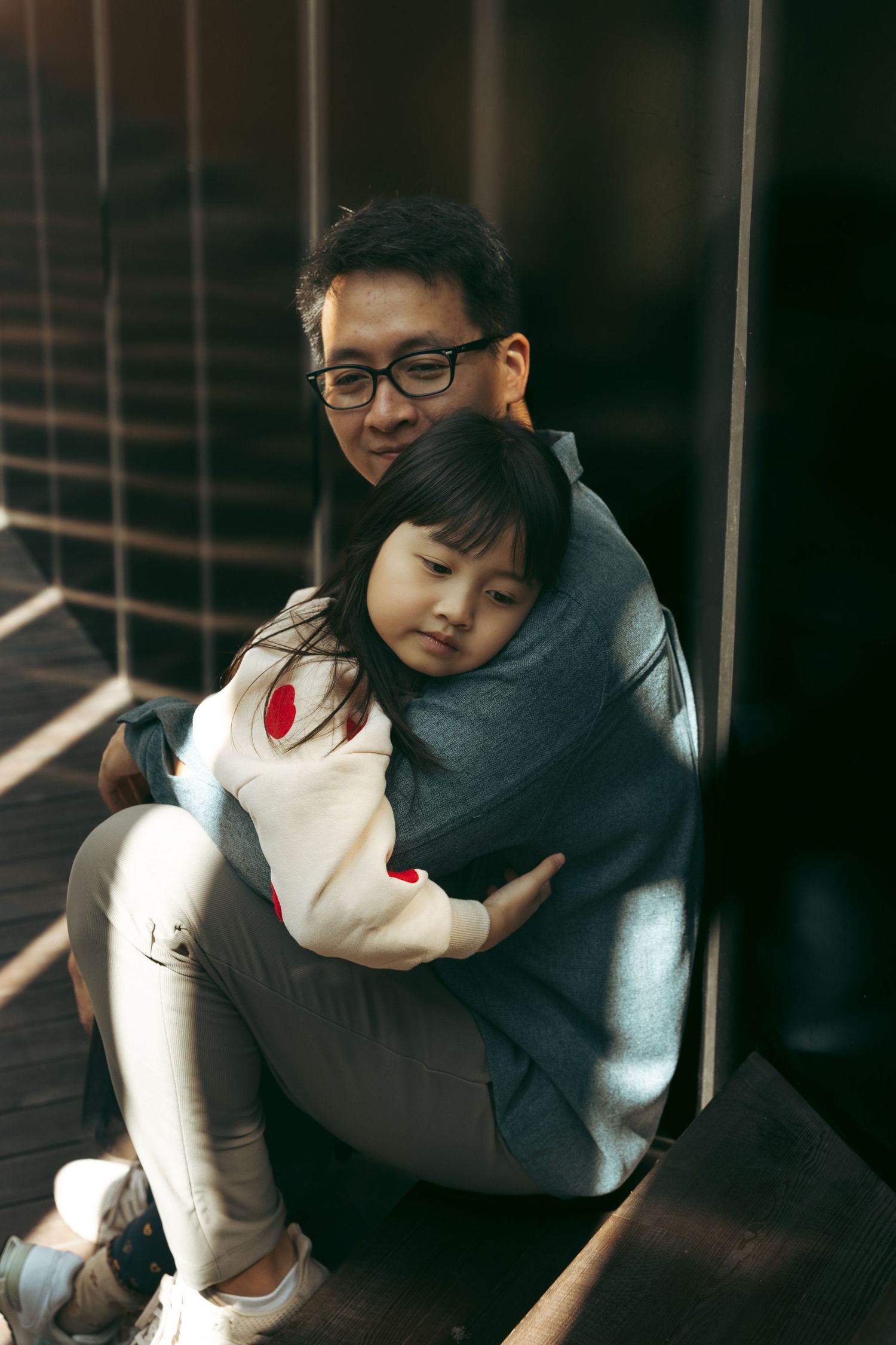 A series of intimate moments shown in four sequential photos as a couple embraces in soft indoor lighting. hong kong family photographer