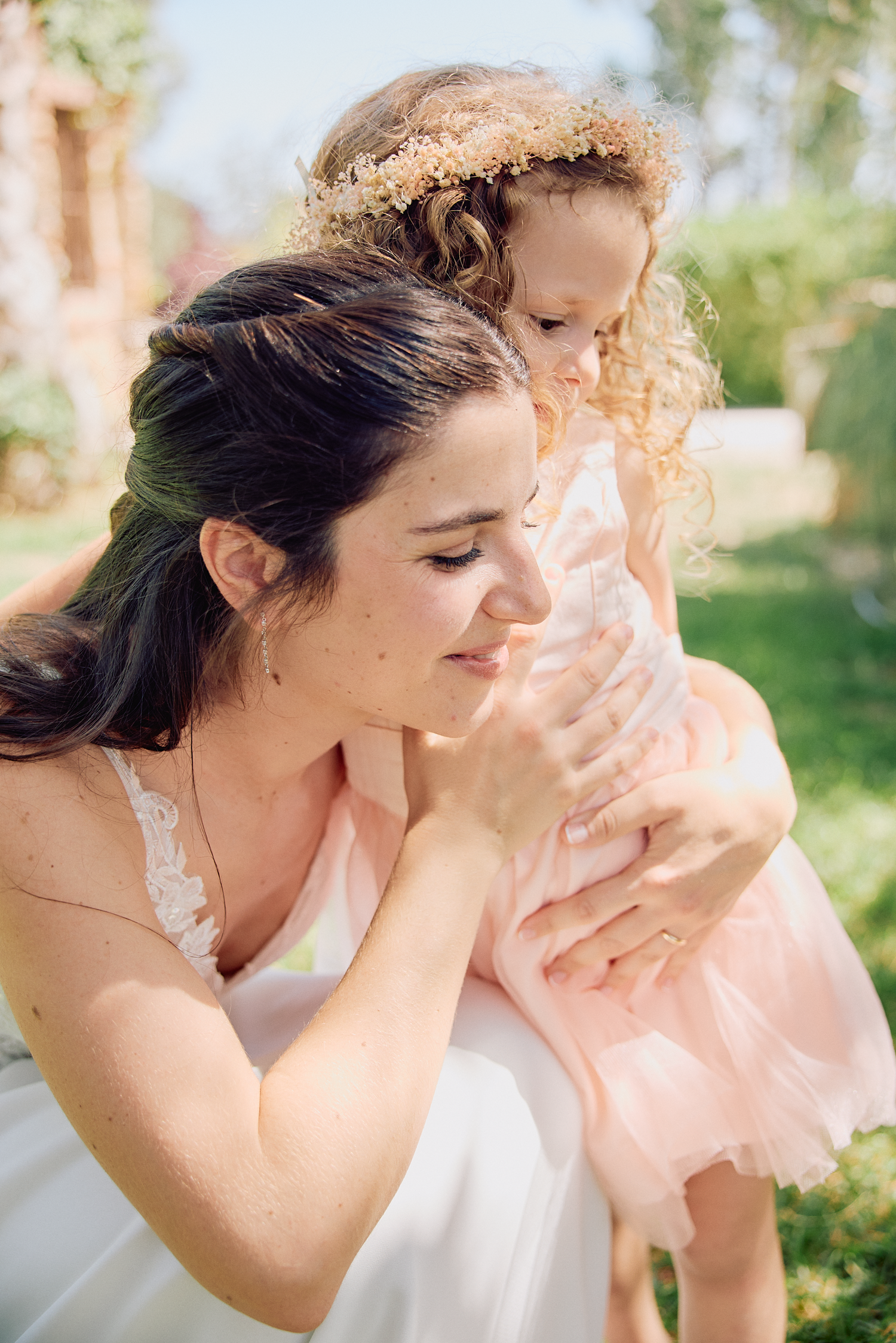 Bride sharing a tender candid moment with a young flower girl during a Barcelona wedding.