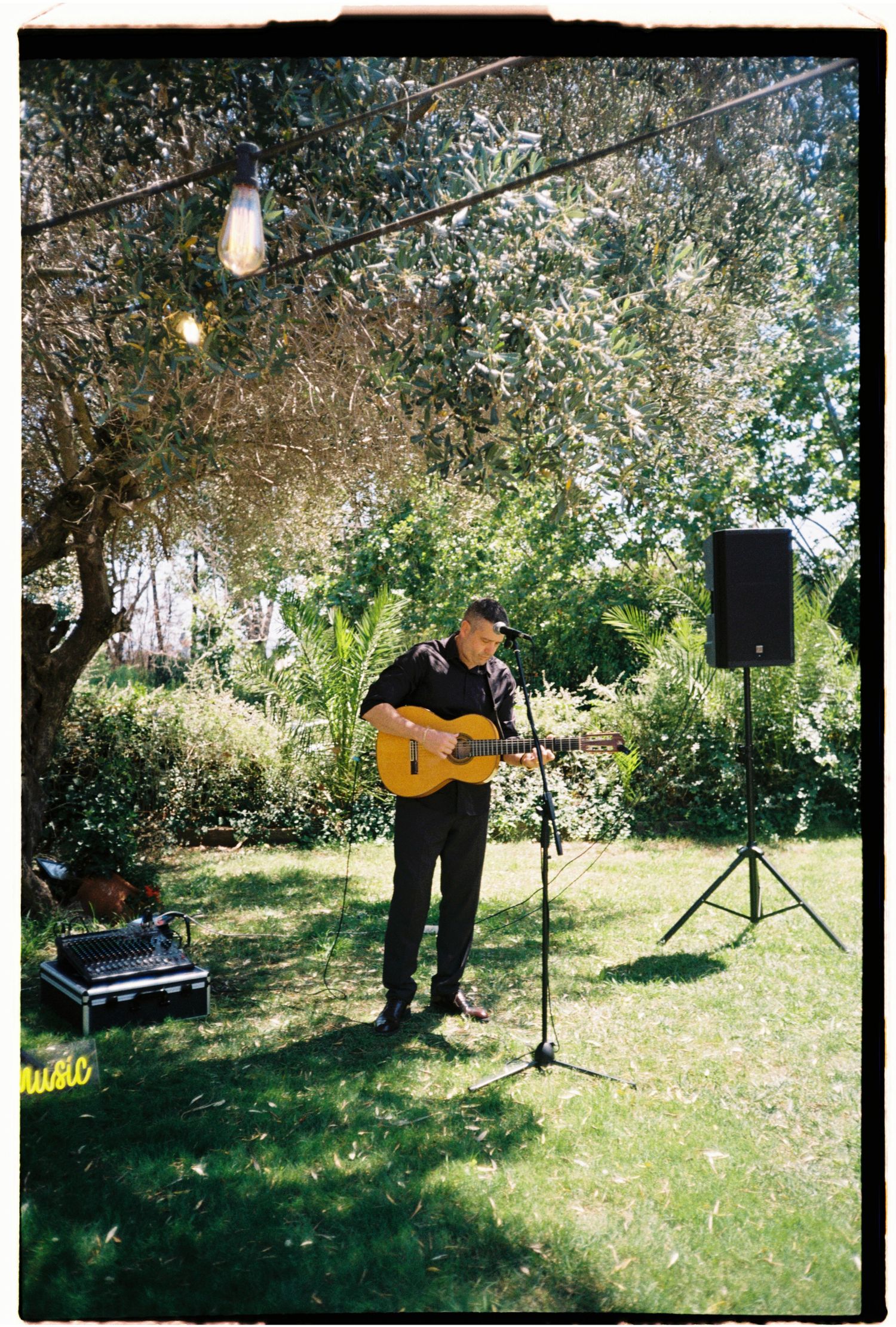 Live musician performing beneath the trees during an intimate outdoor wedding ceremony in Barcelona.