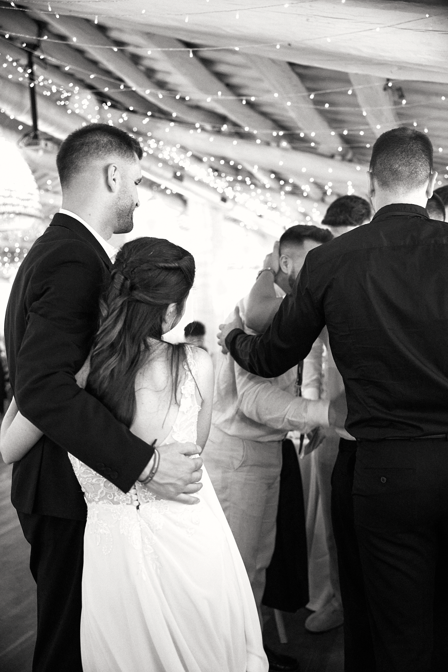Black and white candid photograph of the bride dancing with wedding guests during the reception.