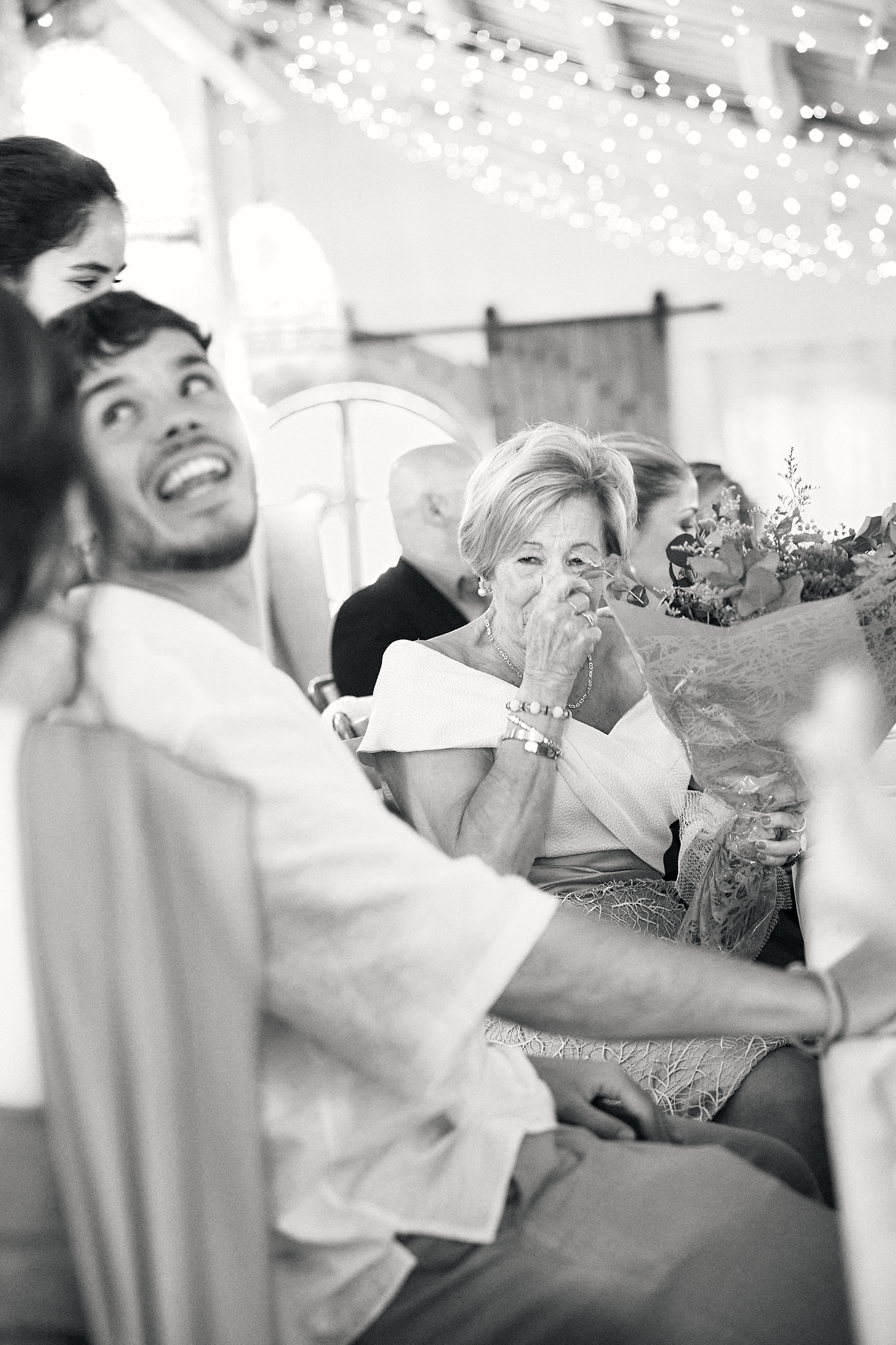 Black and white candid photograph of joyful wedding guests celebrating during the reception.