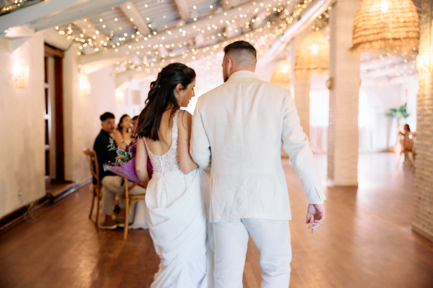 Bride and groom walking hand in hand through their wedding reception in Barcelona, Spain.