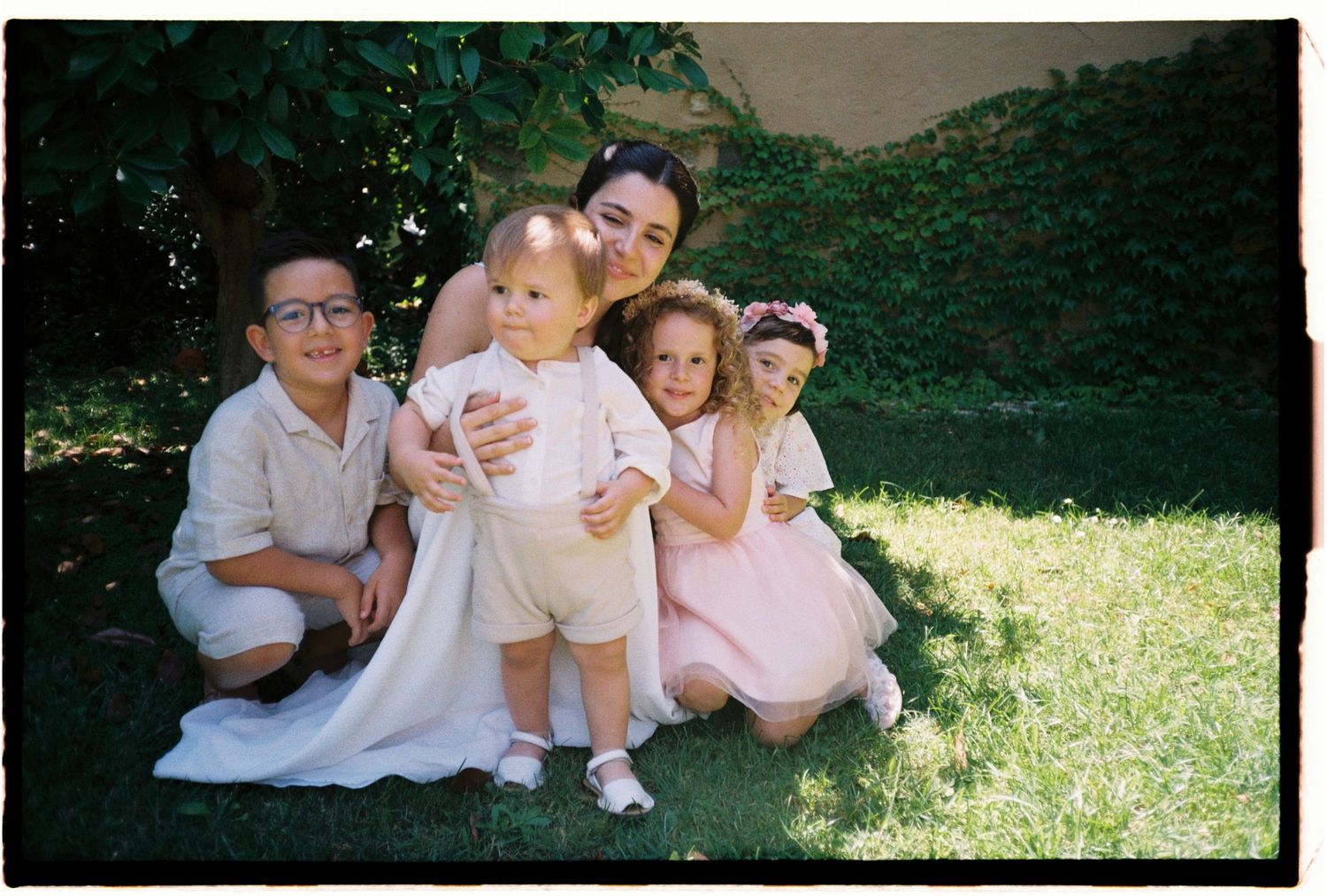 Candid film photograph of children together on the lawn during an intimate outdoor wedding.