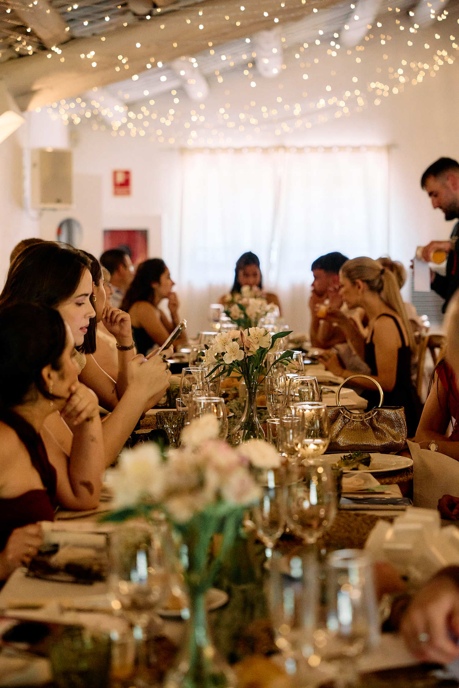 Wedding guests gathered around long dinner tables during a warm and intimate Barcelona wedding reception.